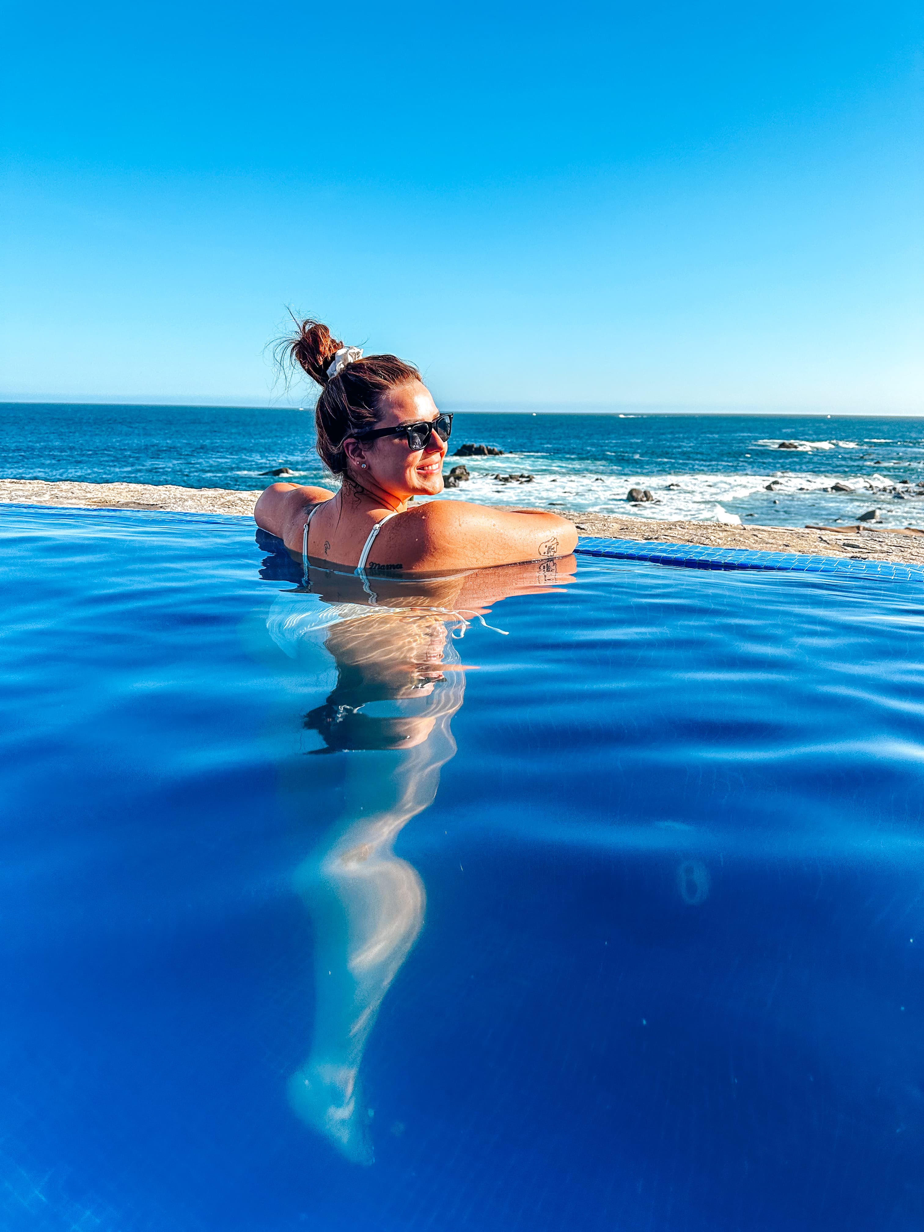 Advisor leaning over the edge of a hotel infinity pool overlooking the beach on a sunny day
