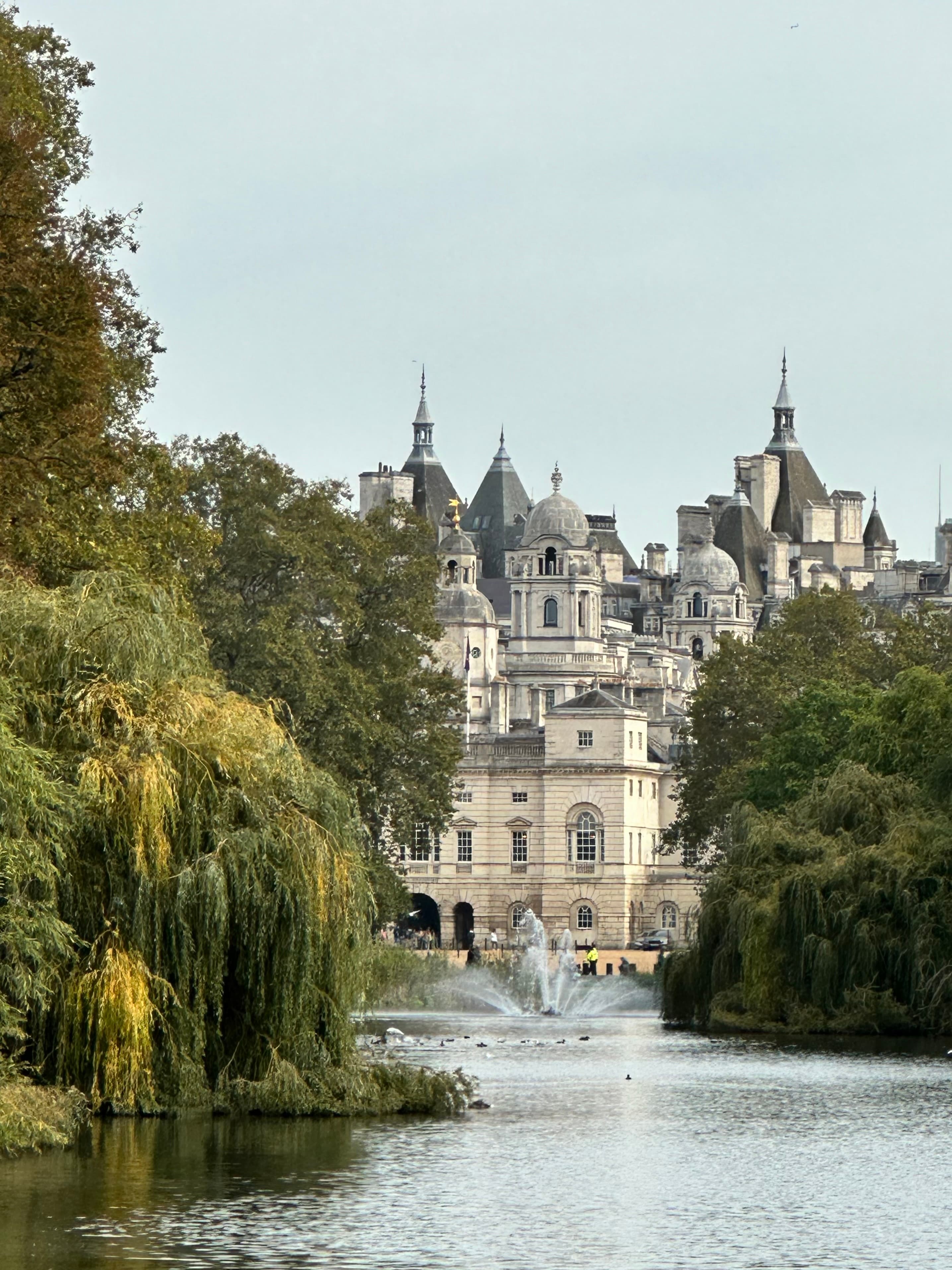 View of a large pond and fountain surrounded by trees and beautiful buildings