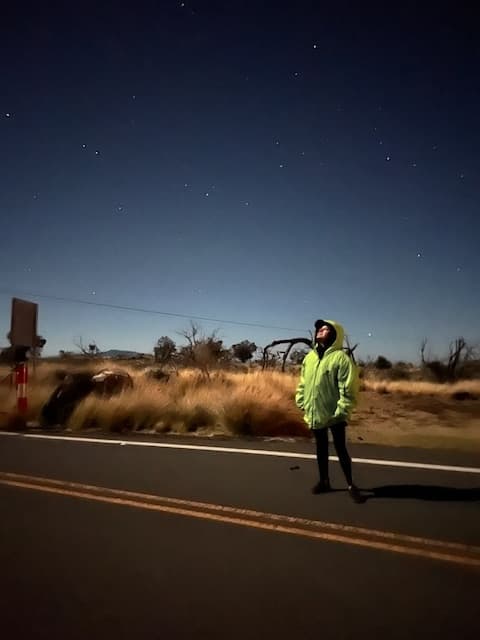 Advisor in a green jacket standing on a highway in the middle of the desert