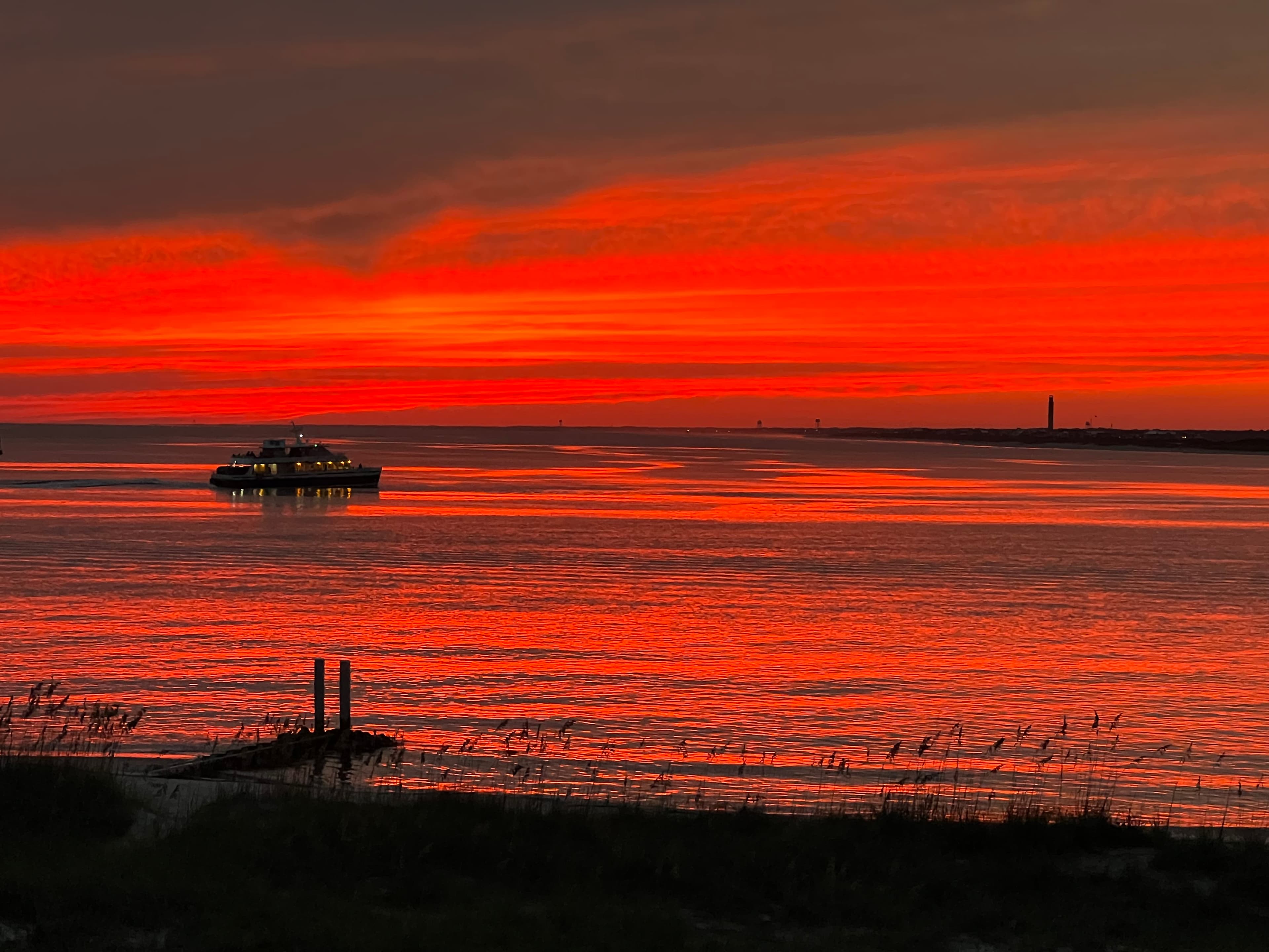 View of a beautiful red sunset over a river with a lone boat on the water