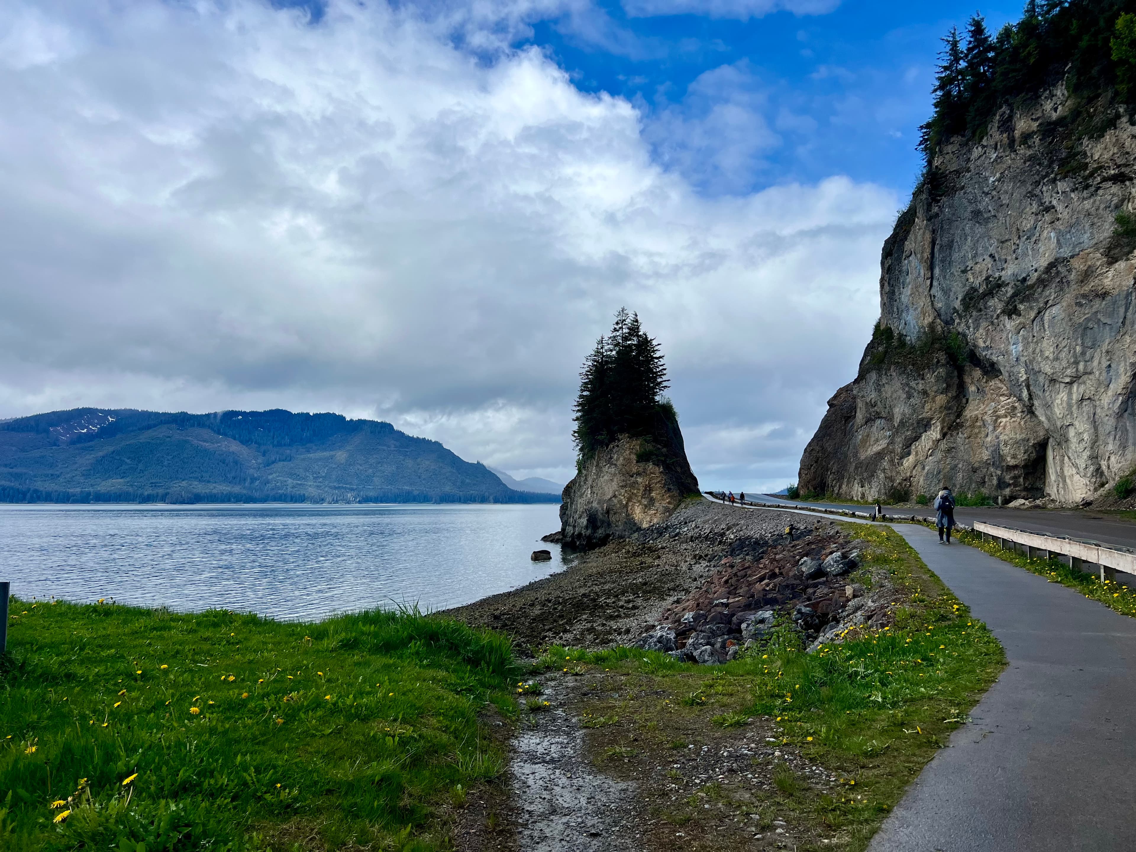View of a scenic coastal pathway beside stunning cliffs on a sunny day