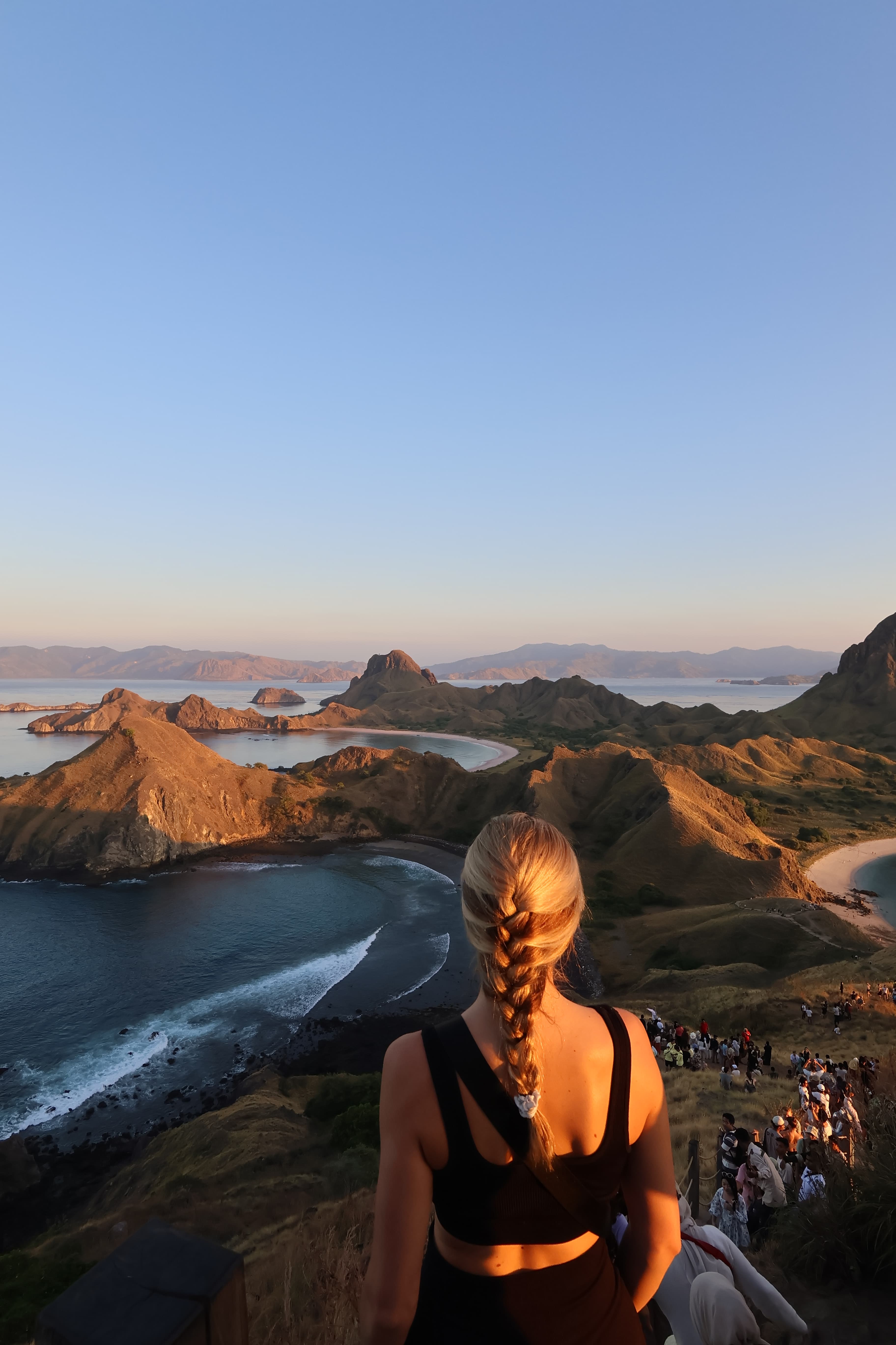 A view of a woman dressed in black athletic wear looking out to a view of mountains at dusk.