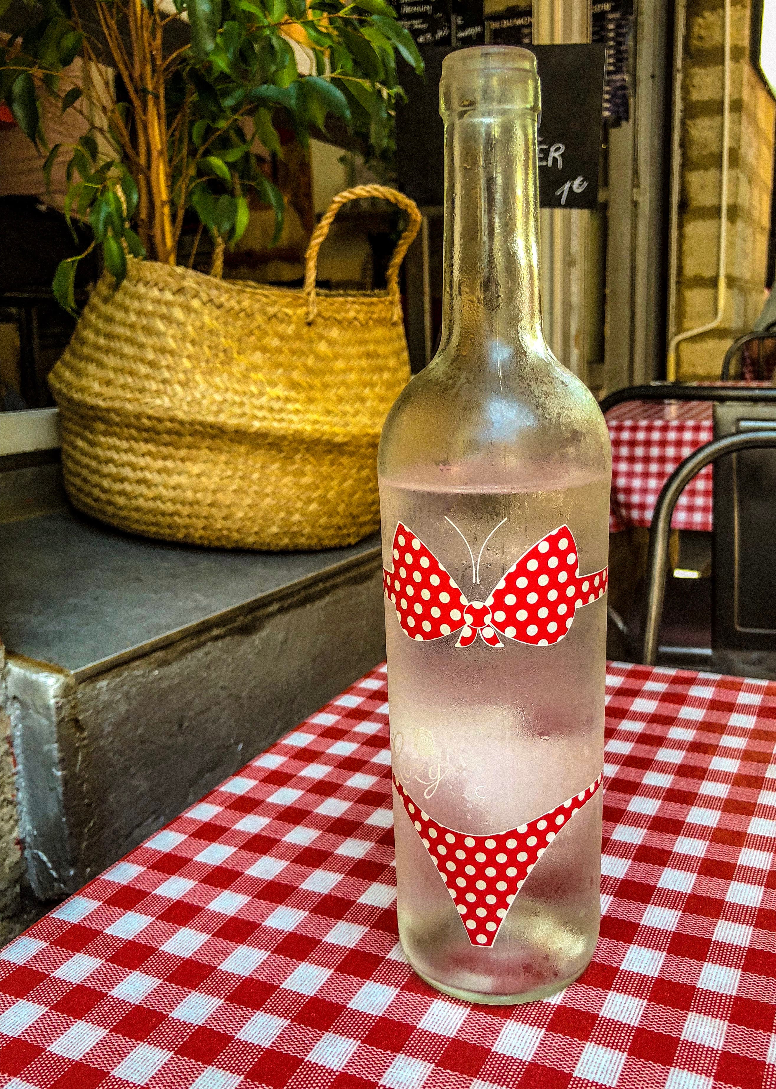 Image of a glass bottle of water with a red and white bikini printed on the side