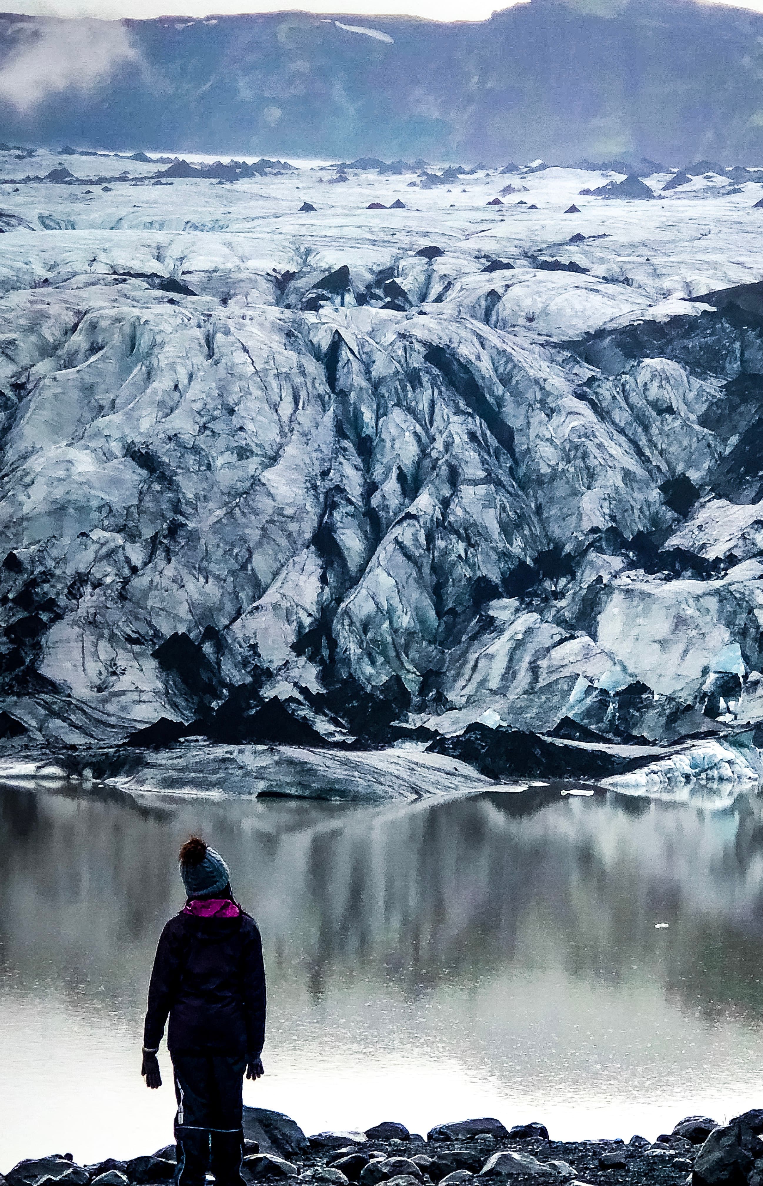 Beautiful view of advisor on a hike overlooking a glassy lake and icy mountains