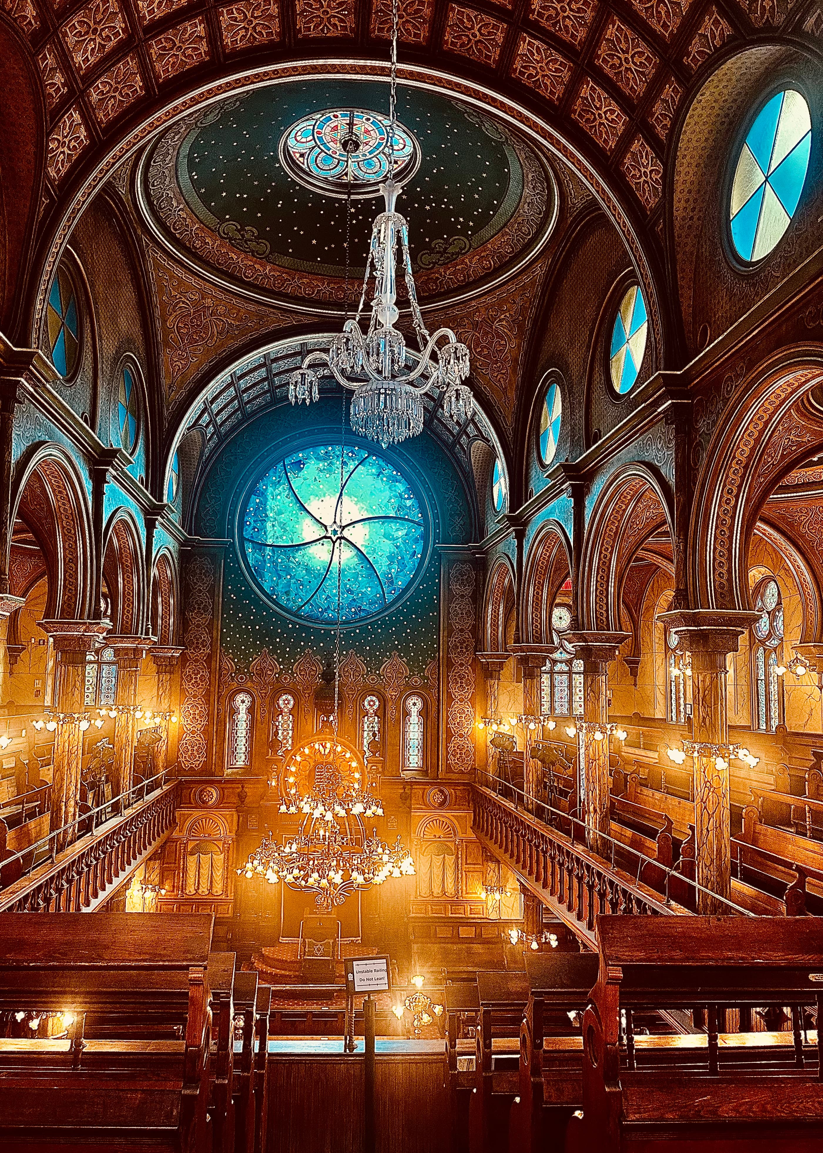 View of the interior of a large church and hanging chandelier lit up by candlelit