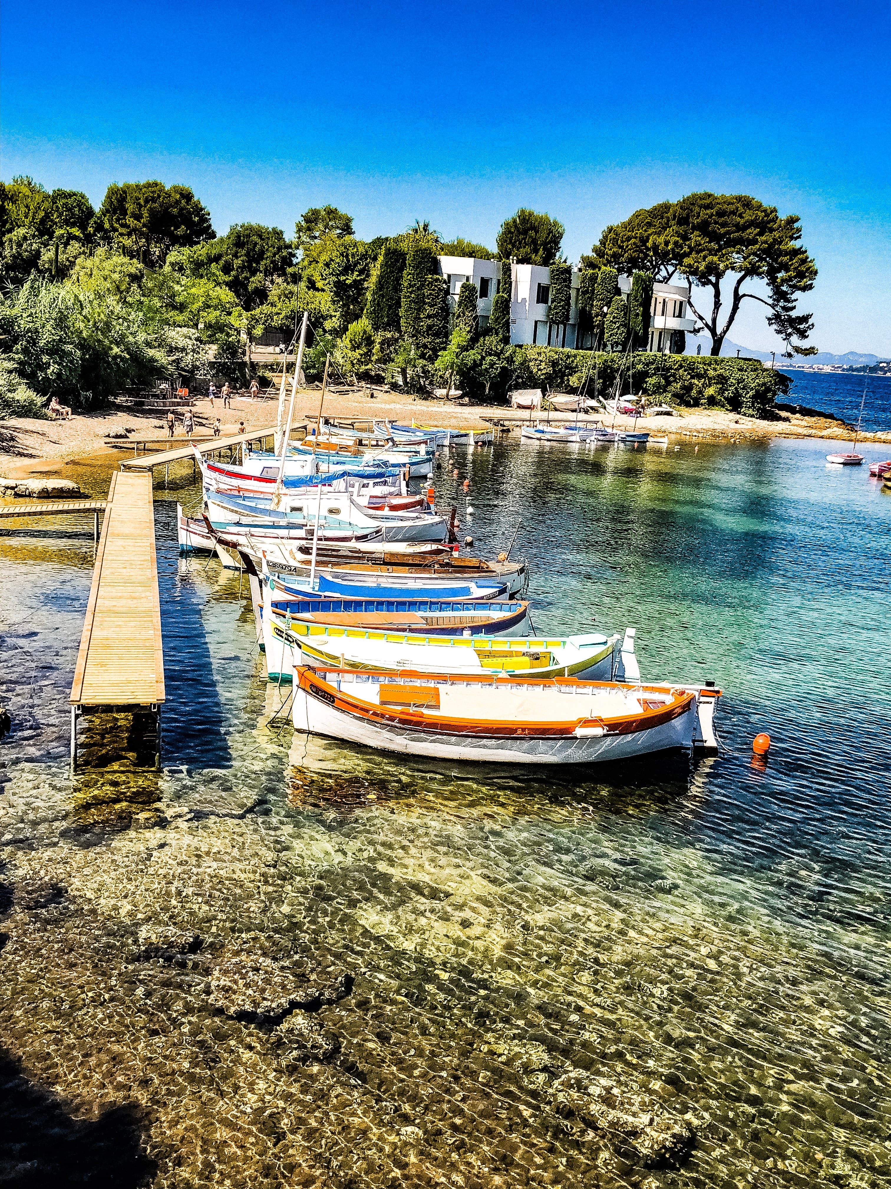 A line of small boats docked side by side in shallow ocean water on a sunny day