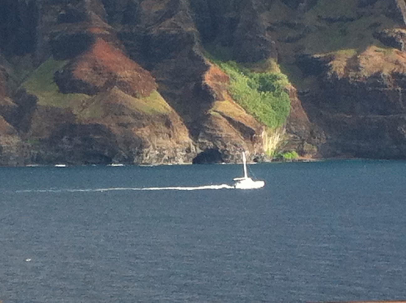 View of a white boat at sea beside stunning rocky cliffs