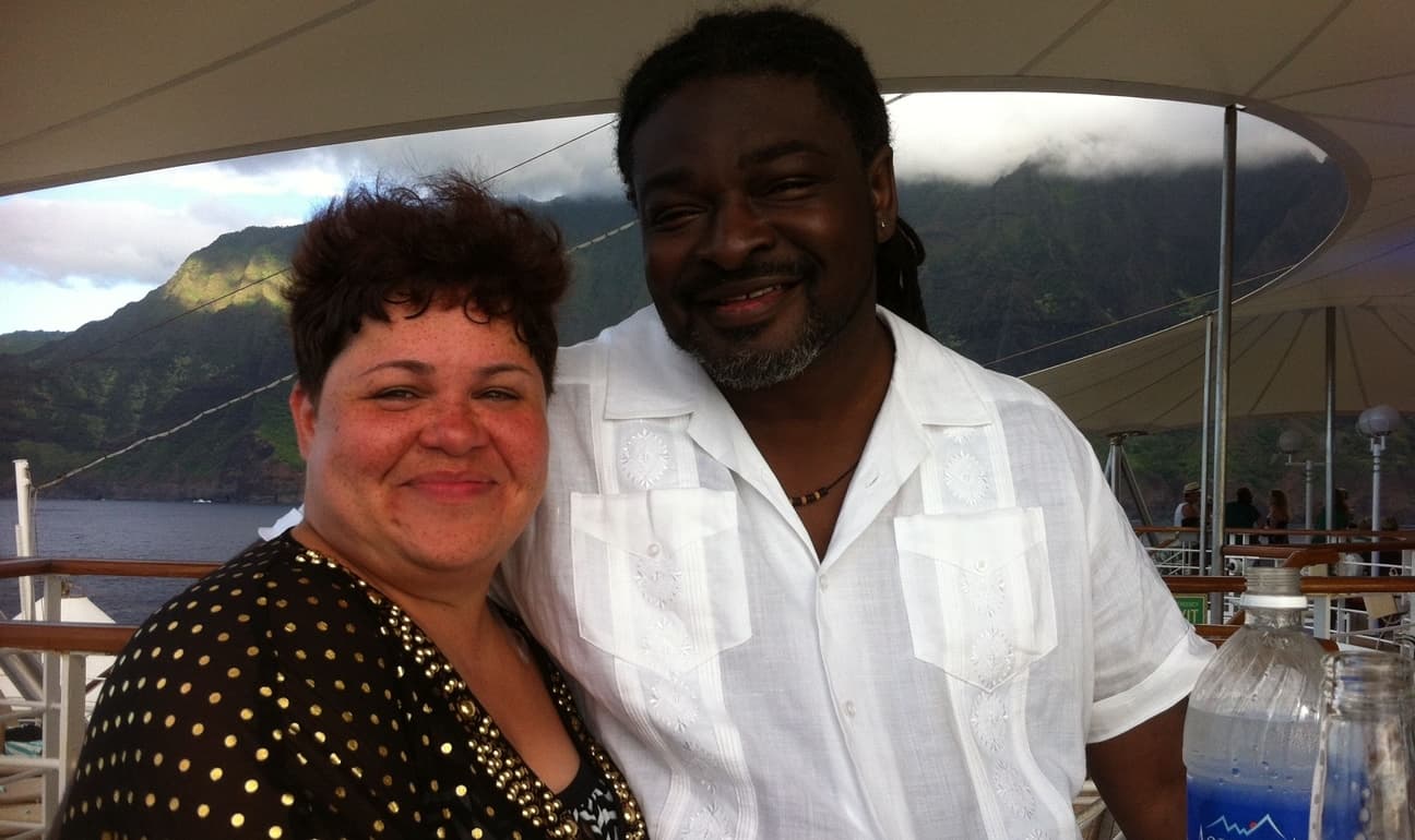 Advisor and partner side by side on a cruise through a tropical area, lush mountains visible in the distance