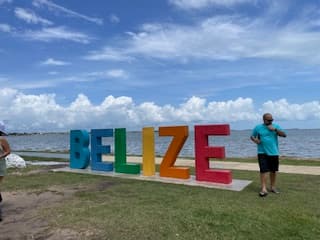 View of rainbow letters spelling BELIZE with the ocean in the background on a sunny day