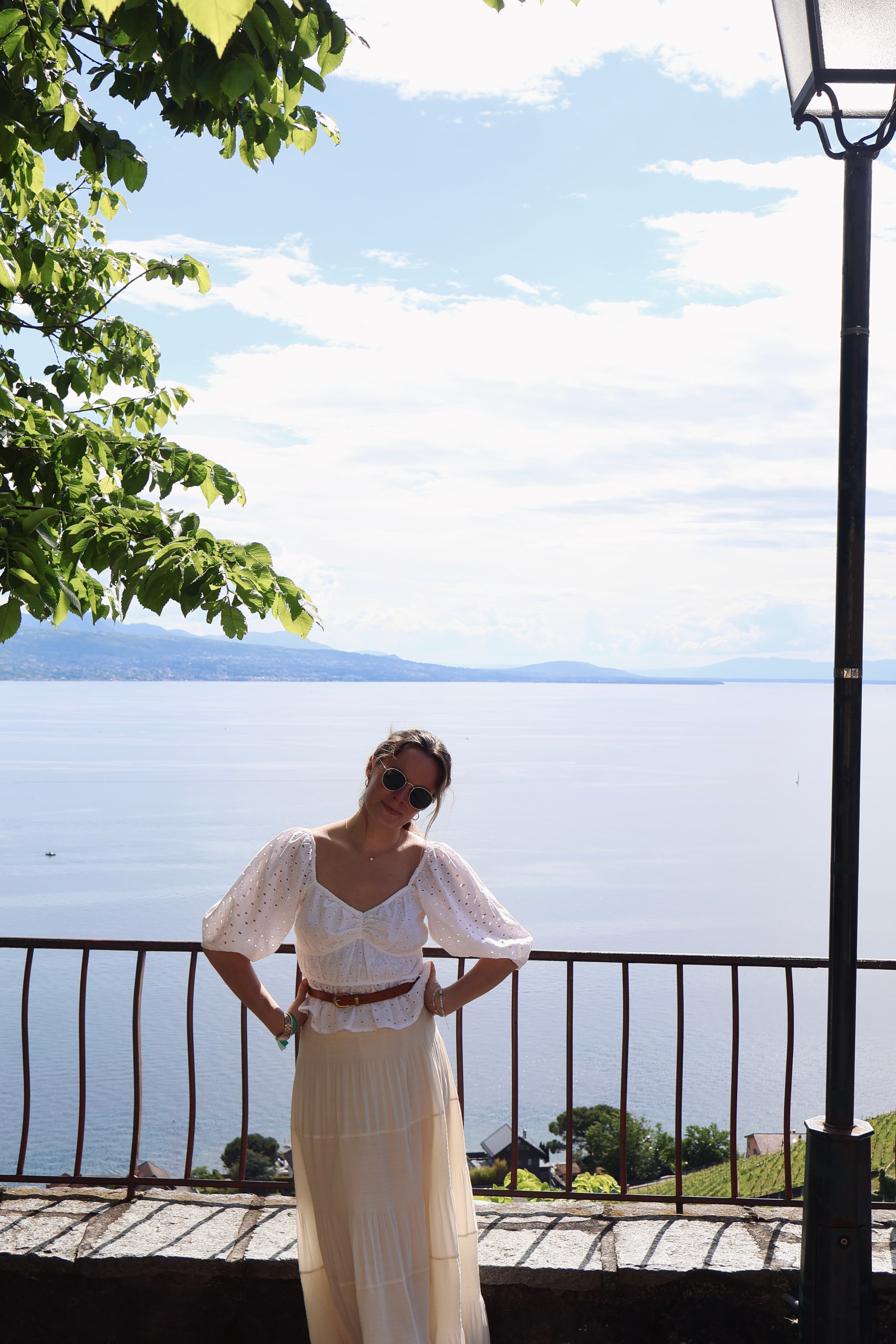 Advisor dressed in all white with hands on her hips posing in front of a large lake during the day