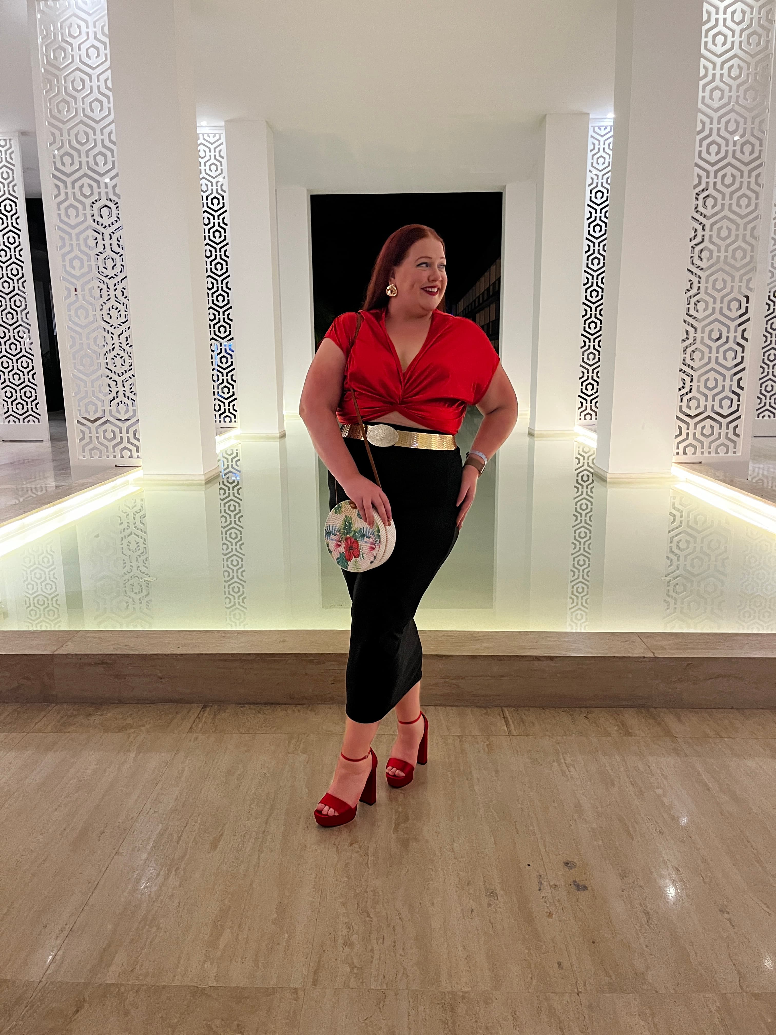 Advisor in a red shirt and matching heels posing indoors in front of a modern marble fountain