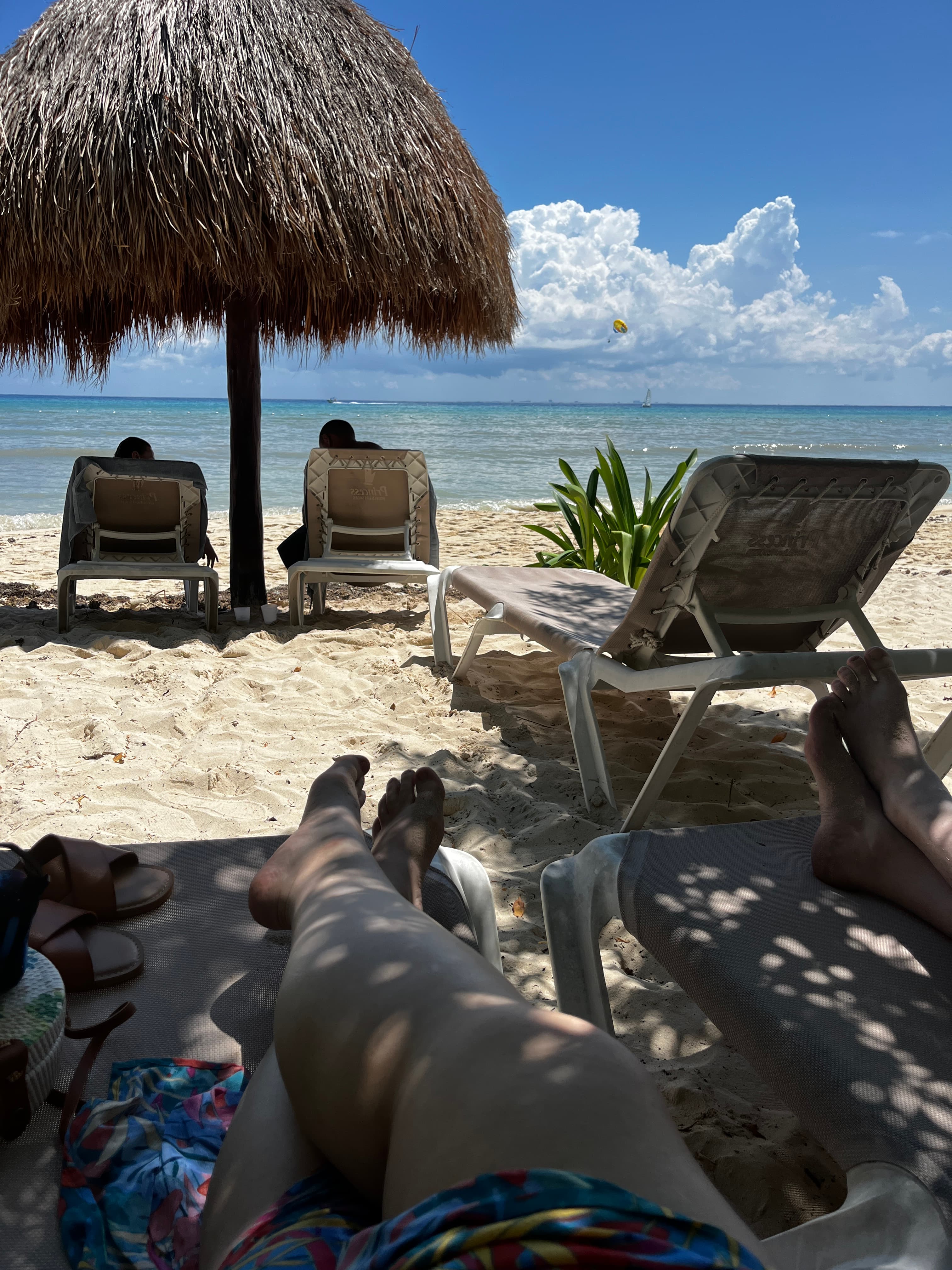 Advisor’s legs stretched out on a lounge chair in the shade on the beach