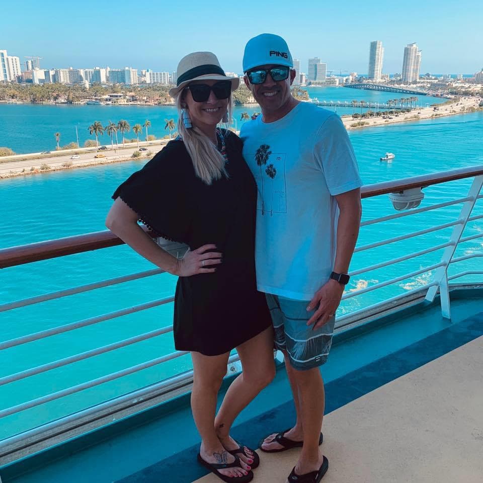 Advisor and her husband smiling side by side on a cruise ship balcony on a sunny day