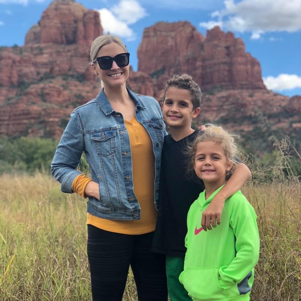 Advisor and her children smiling in a field with beautiful red rock formations behind them