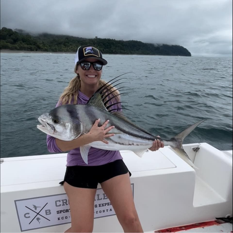 Advisor on a boat holding a large fish on a cloudy day