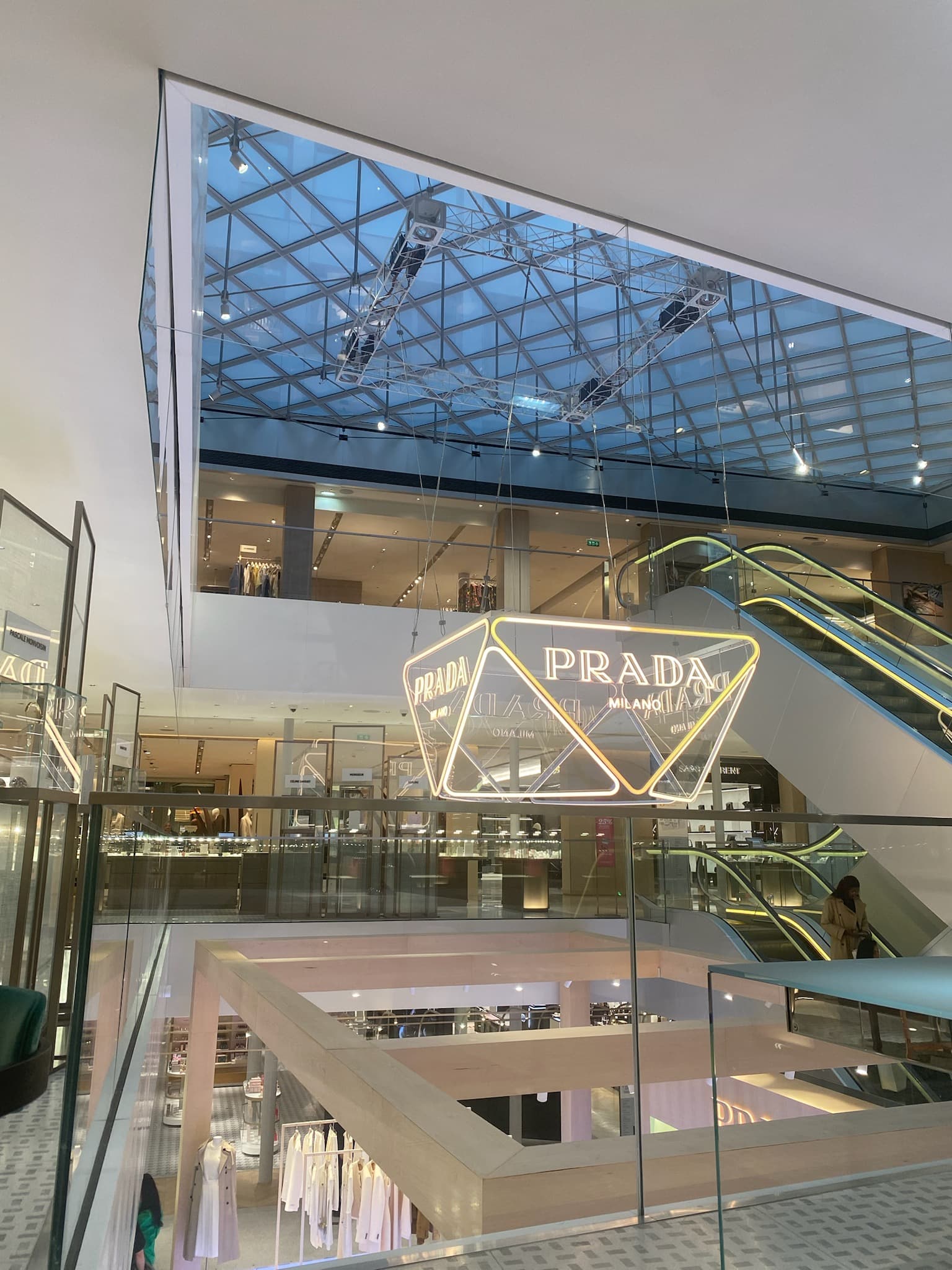 View of the interior of a modern shopping center with a large Prada chandelier in the center