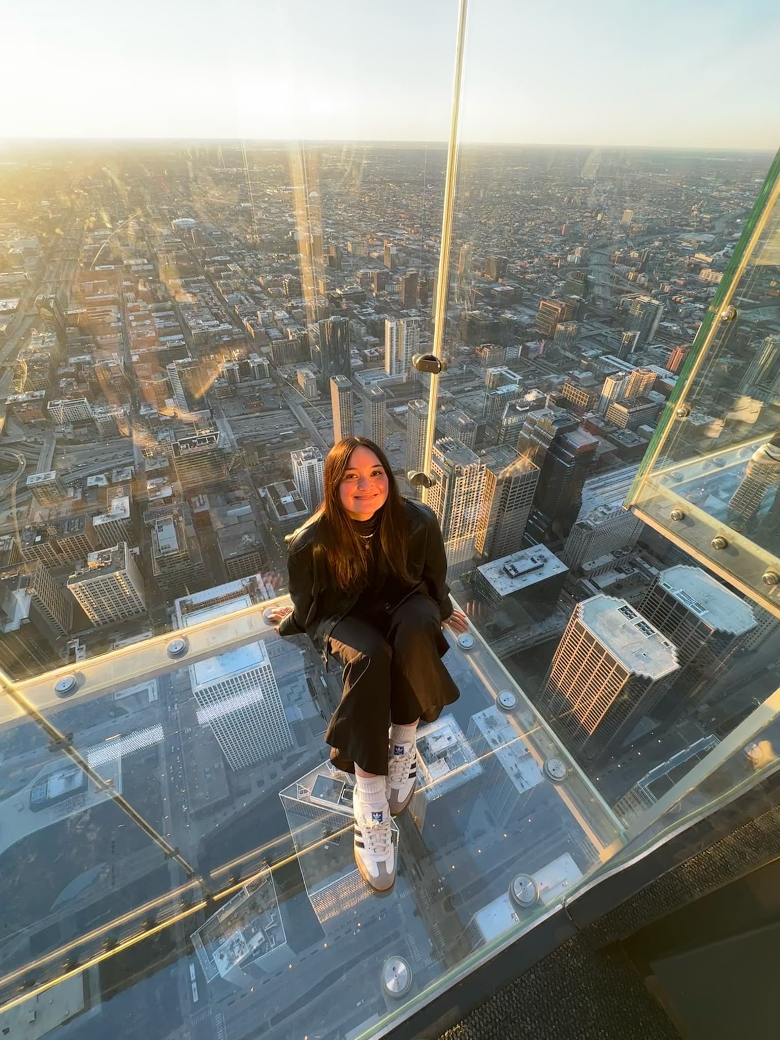 Advisor sitting on the floor of a glass-enclosed viewpoint high above a city at sunset
