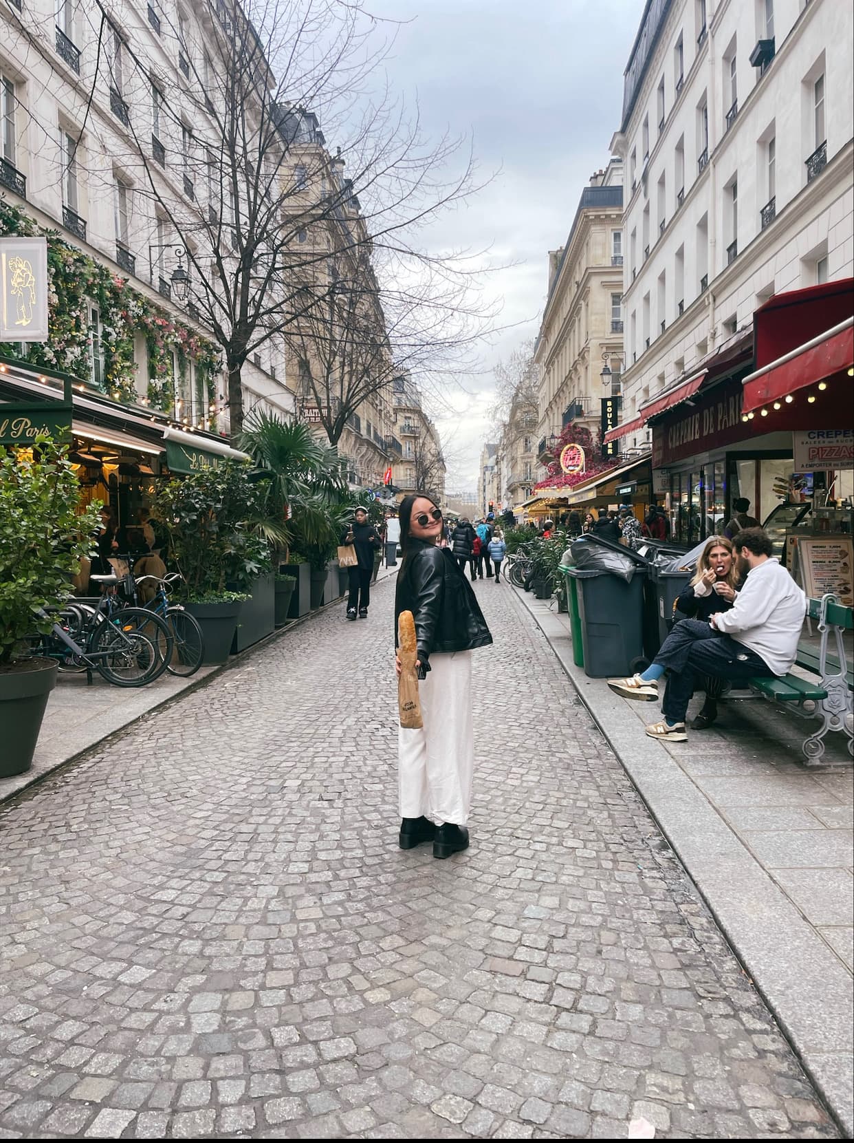 Advisor walking on a cobblestone city street lined with white buildings and outdoor restaurant seating on a cloudy day