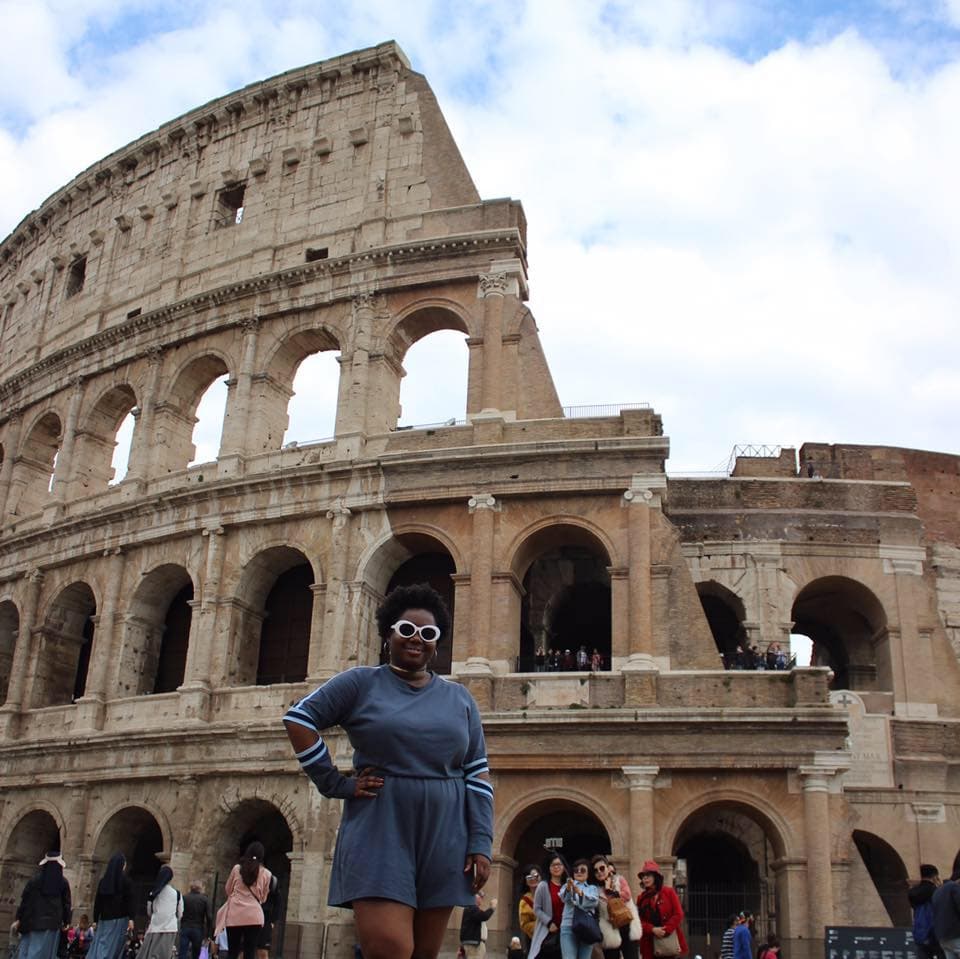 Advisor posing with hand on her hip in front of the Colosseum on a sunny day