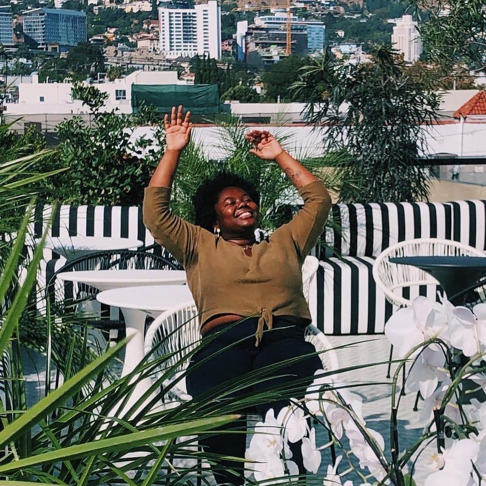 Advisor sitting on a rooftop with arms in the air on a sunny day