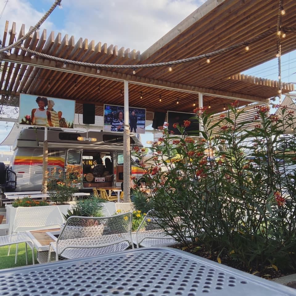 View of a colorful outdoor restaurant seating area filled with plants during the day
