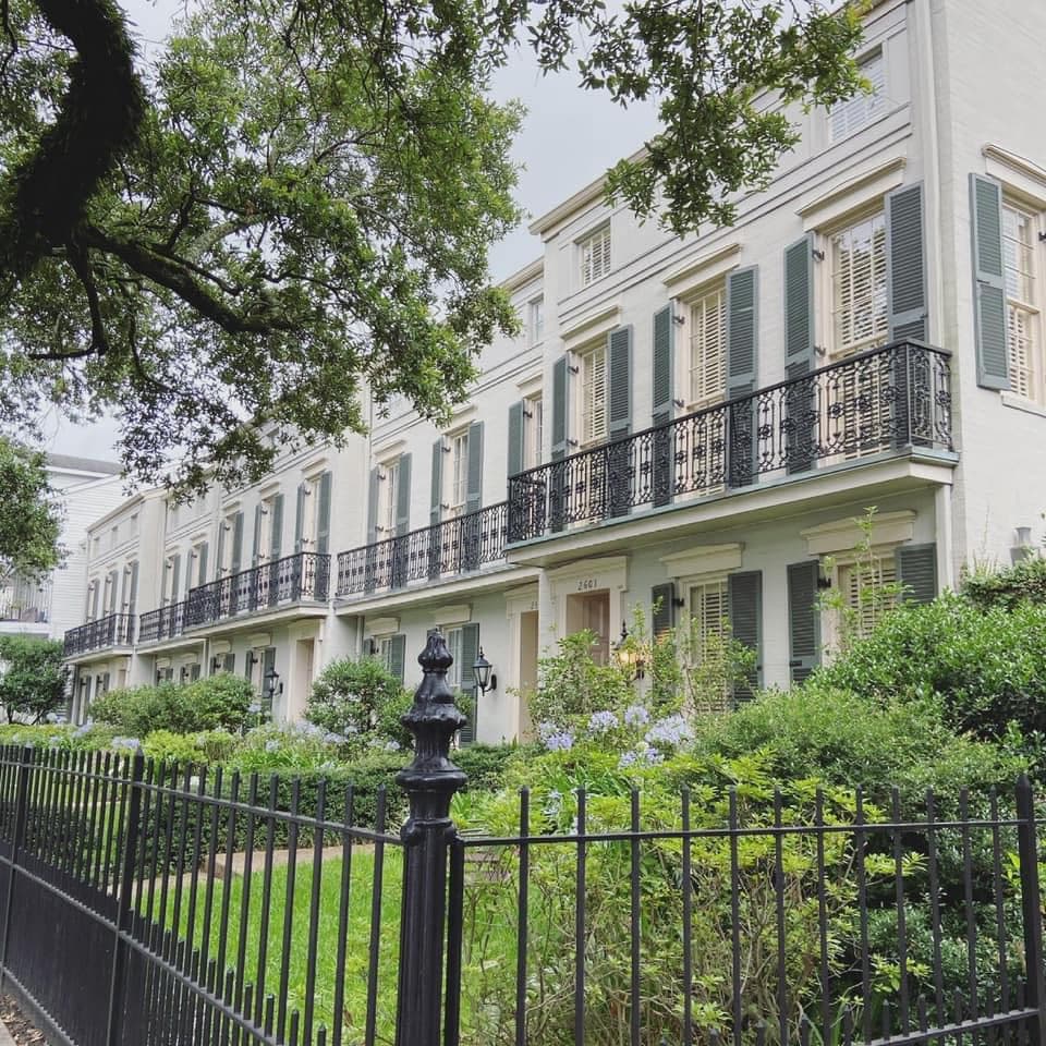 View of a row of pretty white apartment buildings and green front yards