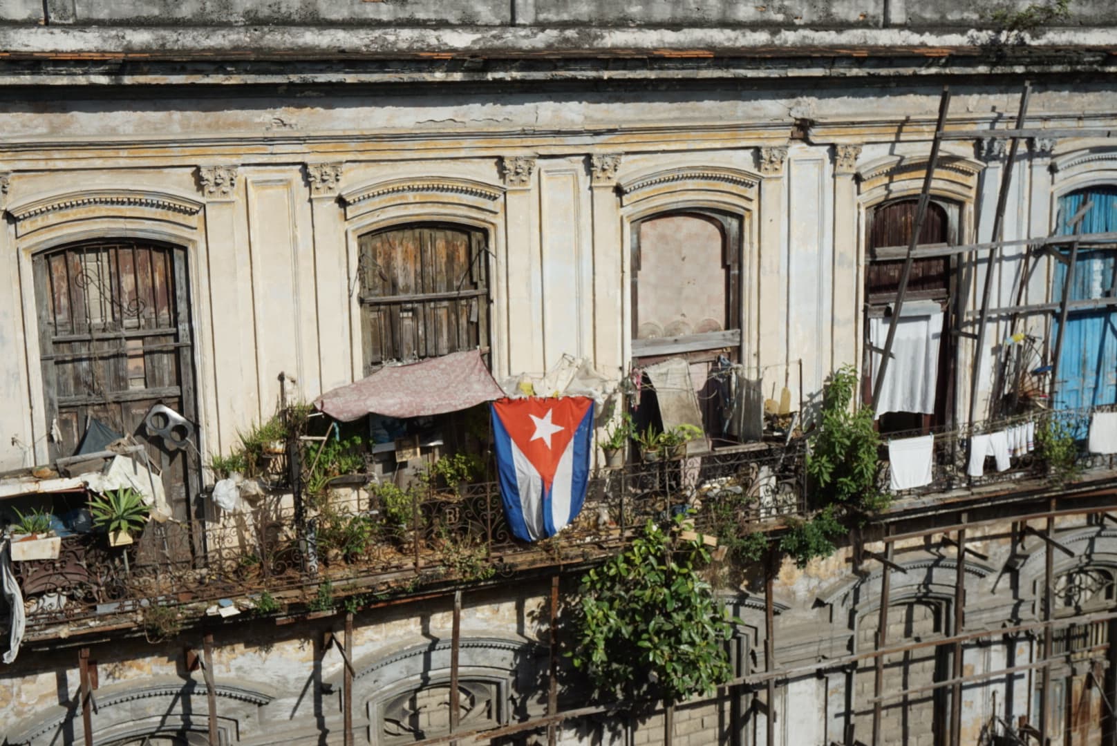 View of the side of an old apartment building with plants and laundry visible hanging from balconies
