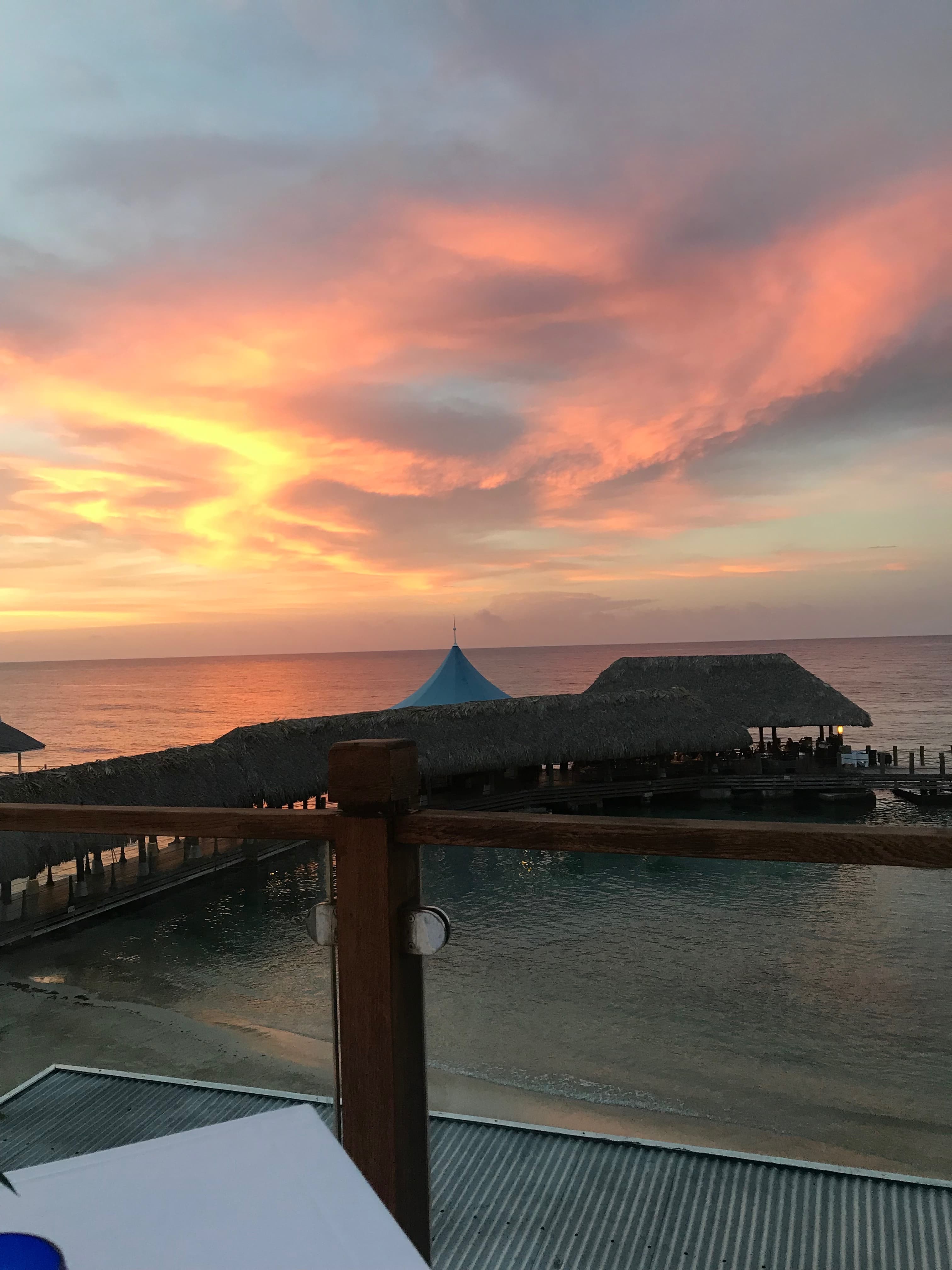 View of the sea and a covered pier seen from a balcony at sunset 