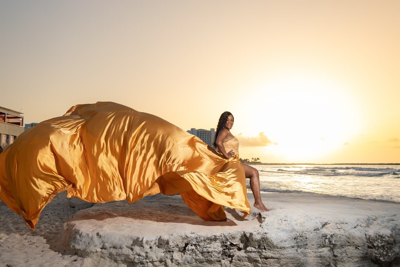 Advisor posing in a gold dress on the beach on a sunny day.