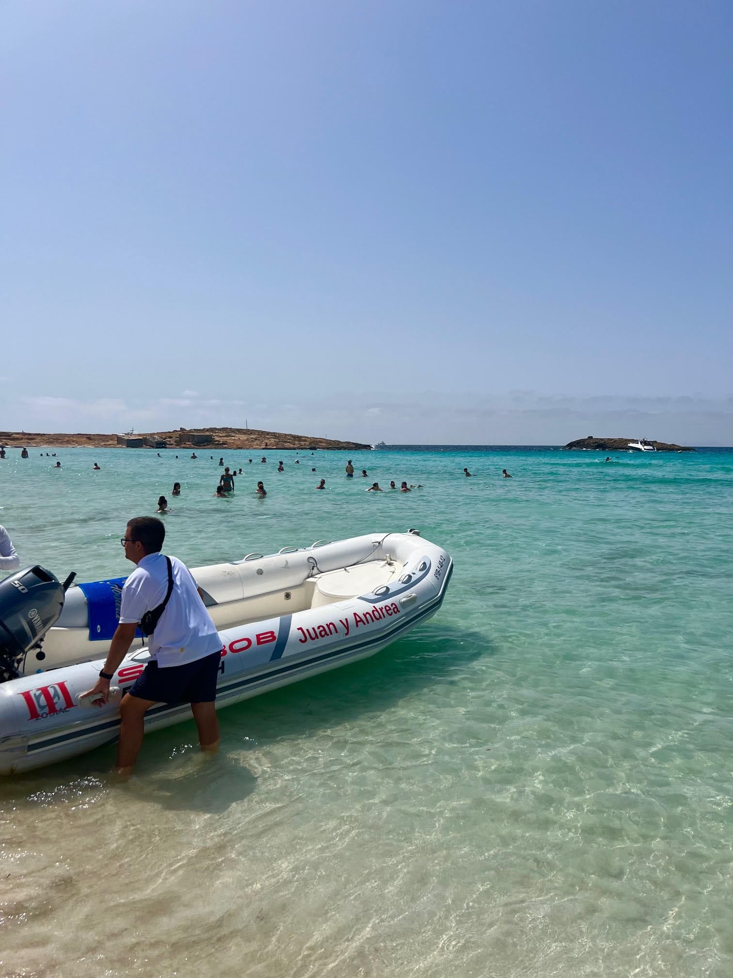 View of a small motorboat on shore a calm crystal clear beach