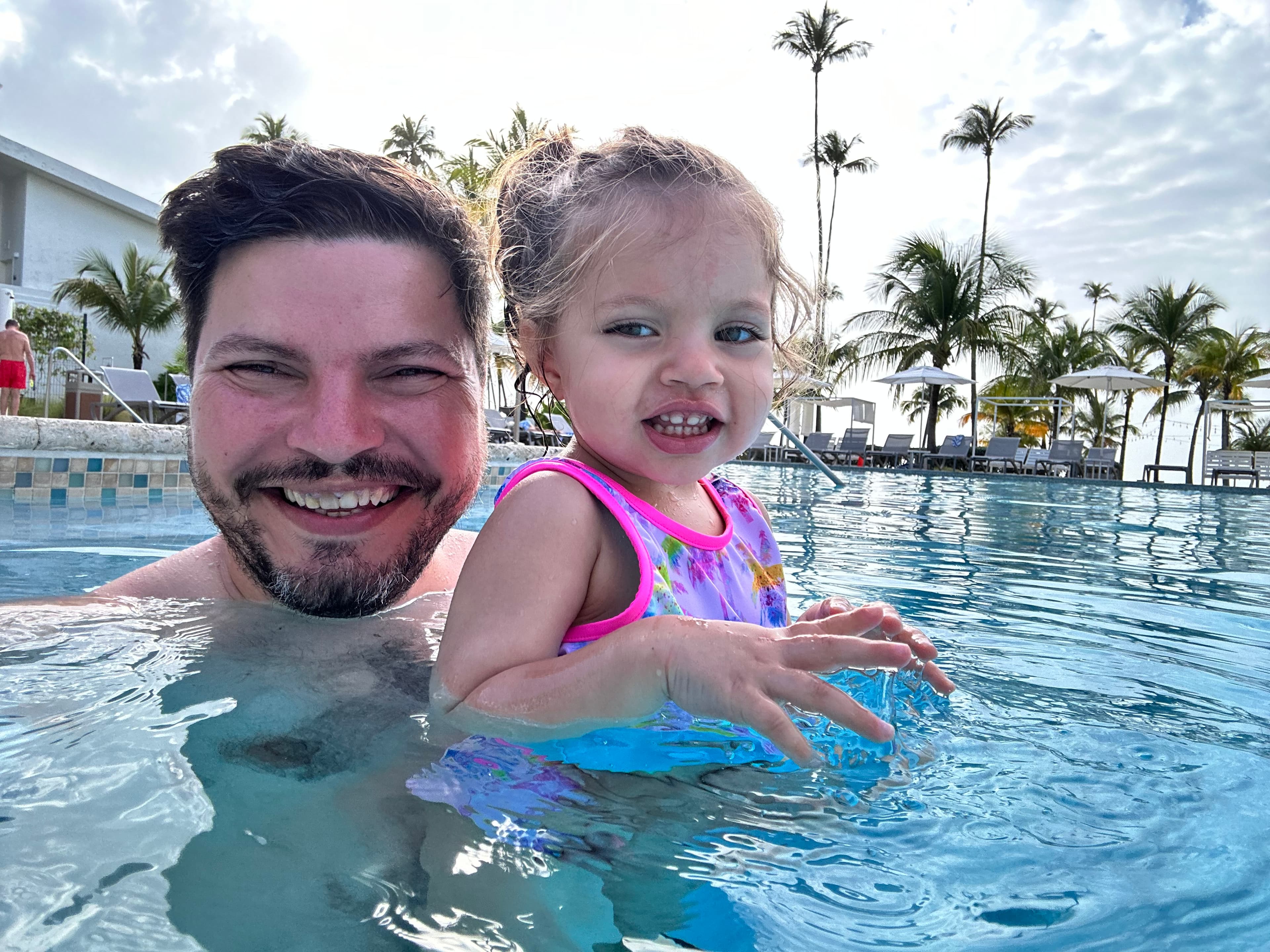 Advisor and his daughter in a resort pool at sunset