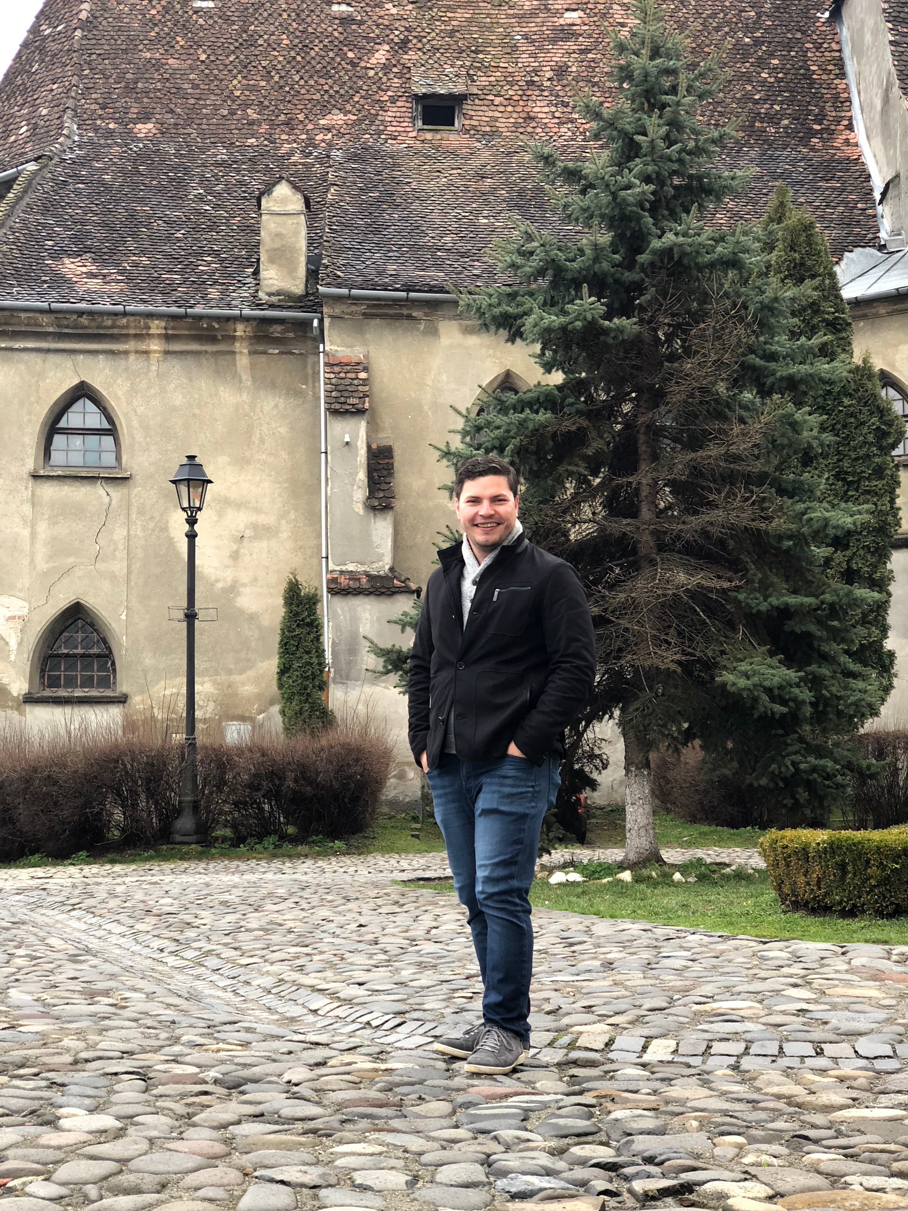 Advisor on a cobblestone street in front of an old building and tree