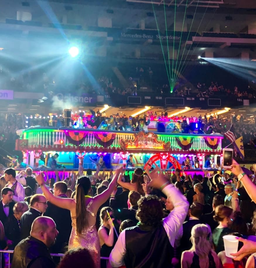 People dancing in a crowded street with neon lights on the buildings.