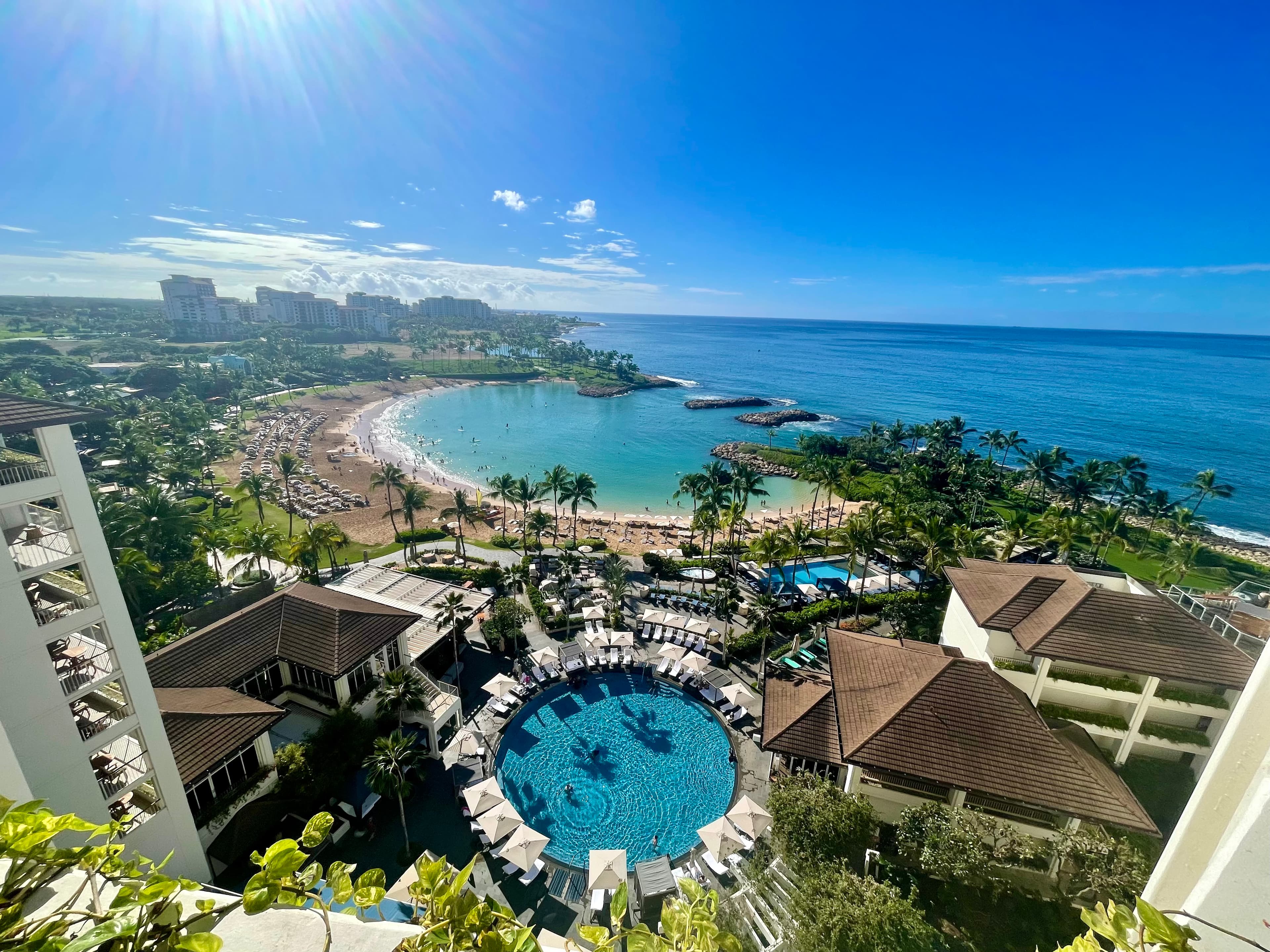 Aerial view of a resort with circular pool in the center and a beautiful bay visible in the distance