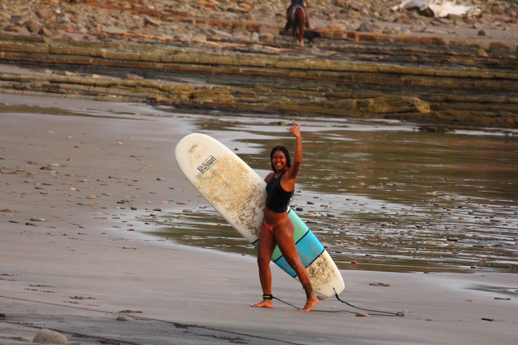 Advisor walking on the beach with a surfboard