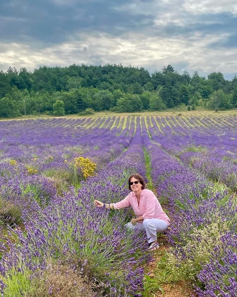 View of advisor squatting in fields of lavender on a cloudy day