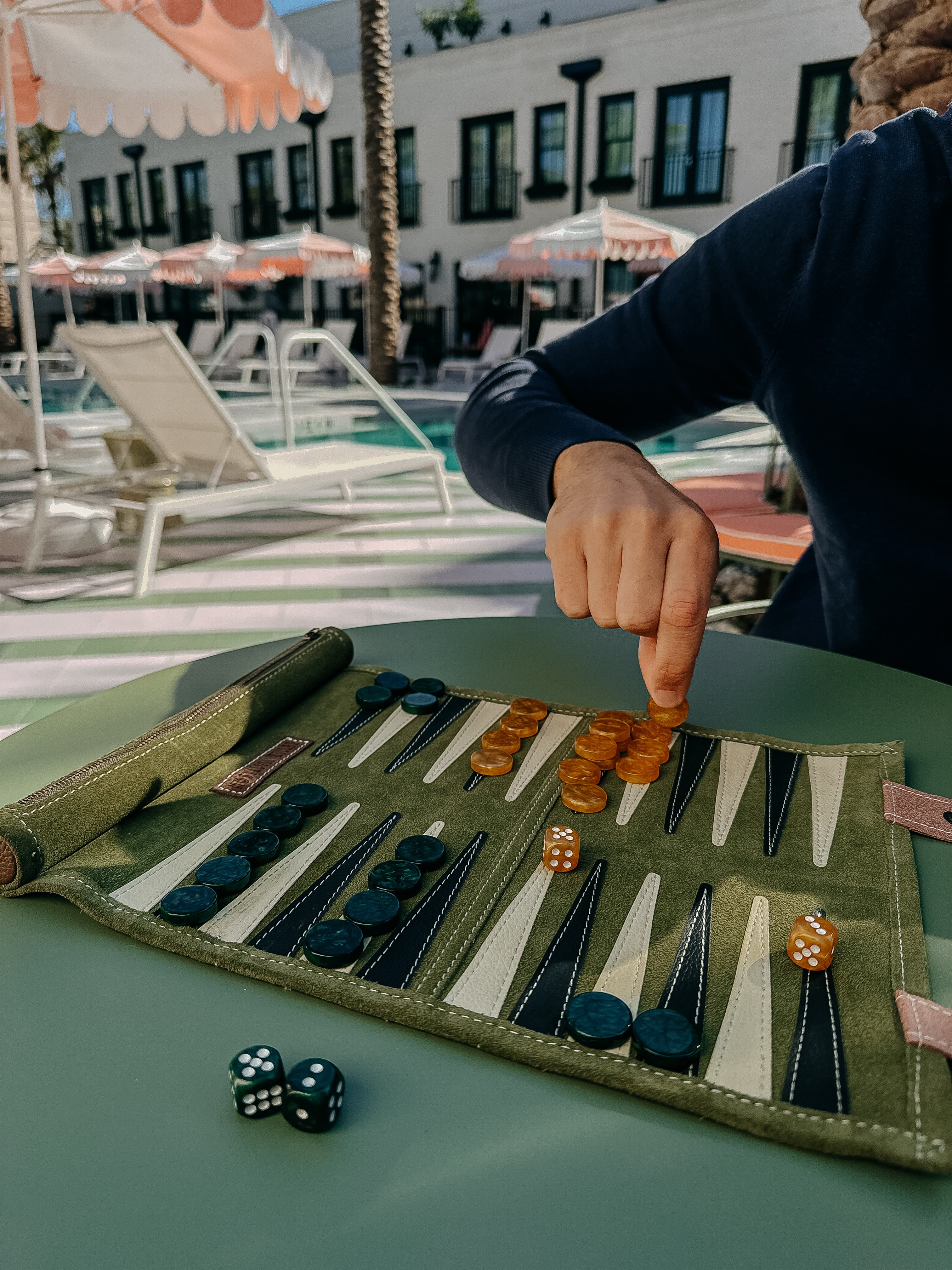 Someone playing a board game by a hotel pool on a sunny day
