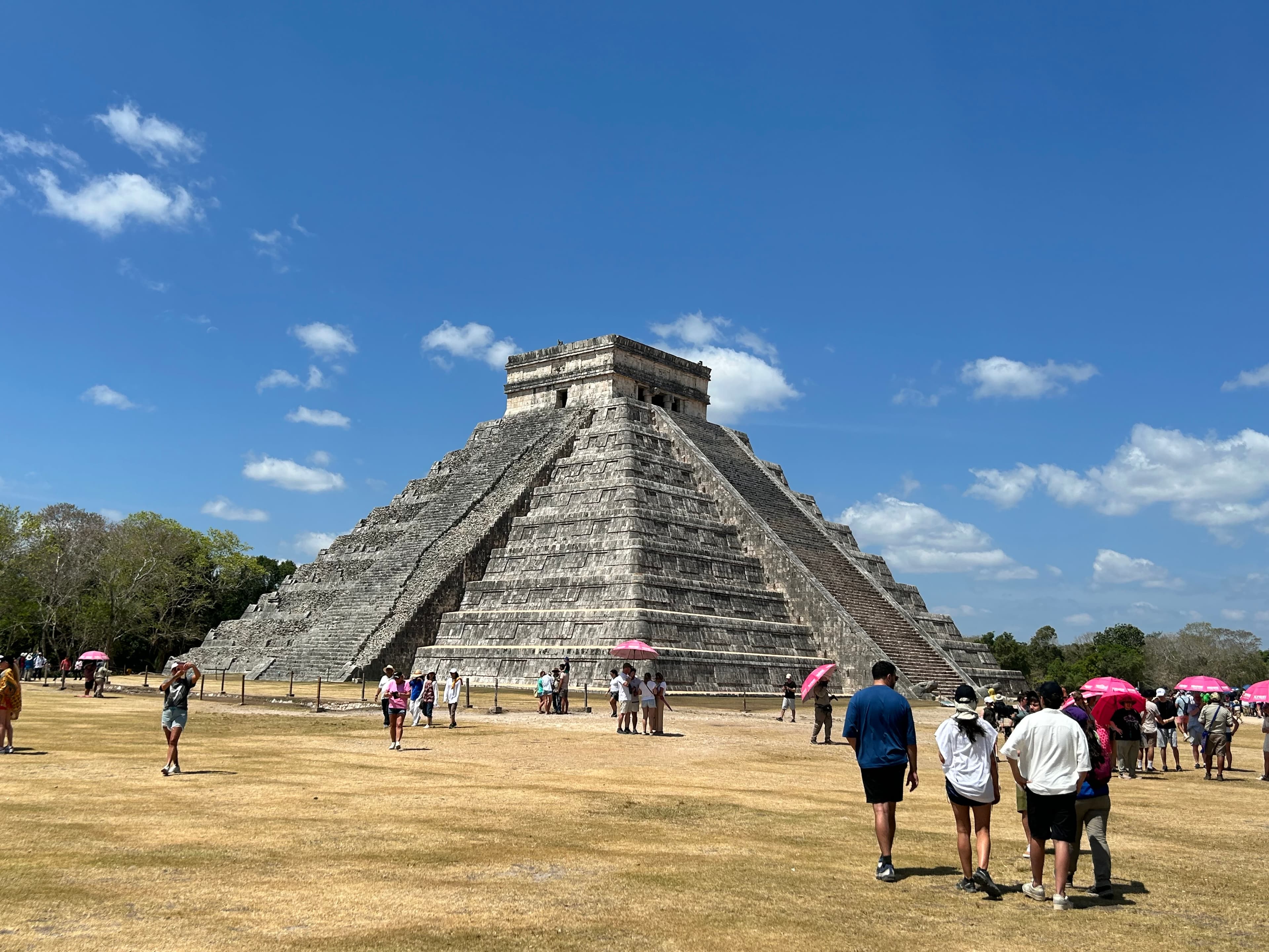A view of a historic temple with tourists walking around in front of it. 