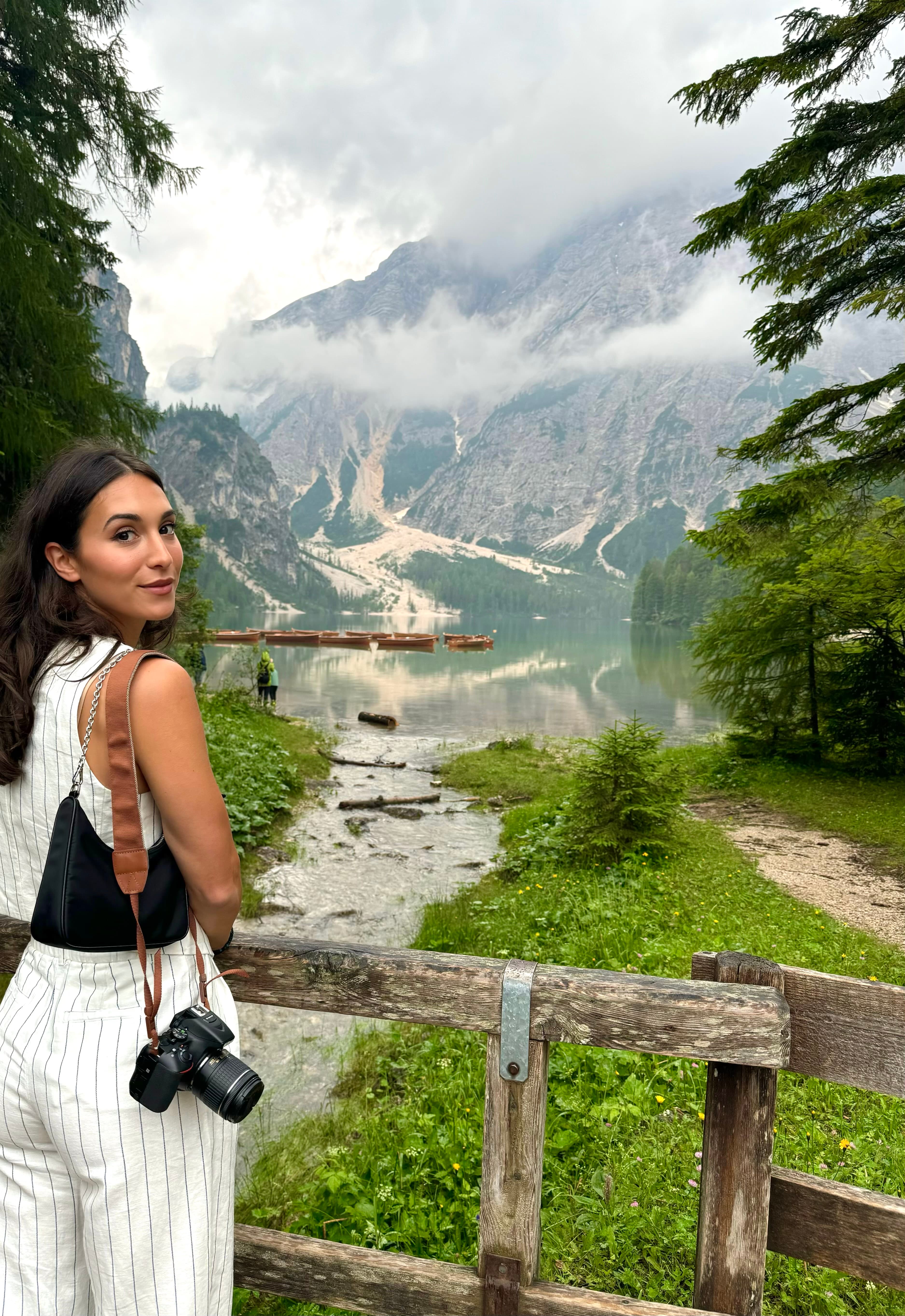 Advisor holding a camera at a viewpoint overlooking a valley and mountains in the distance 
