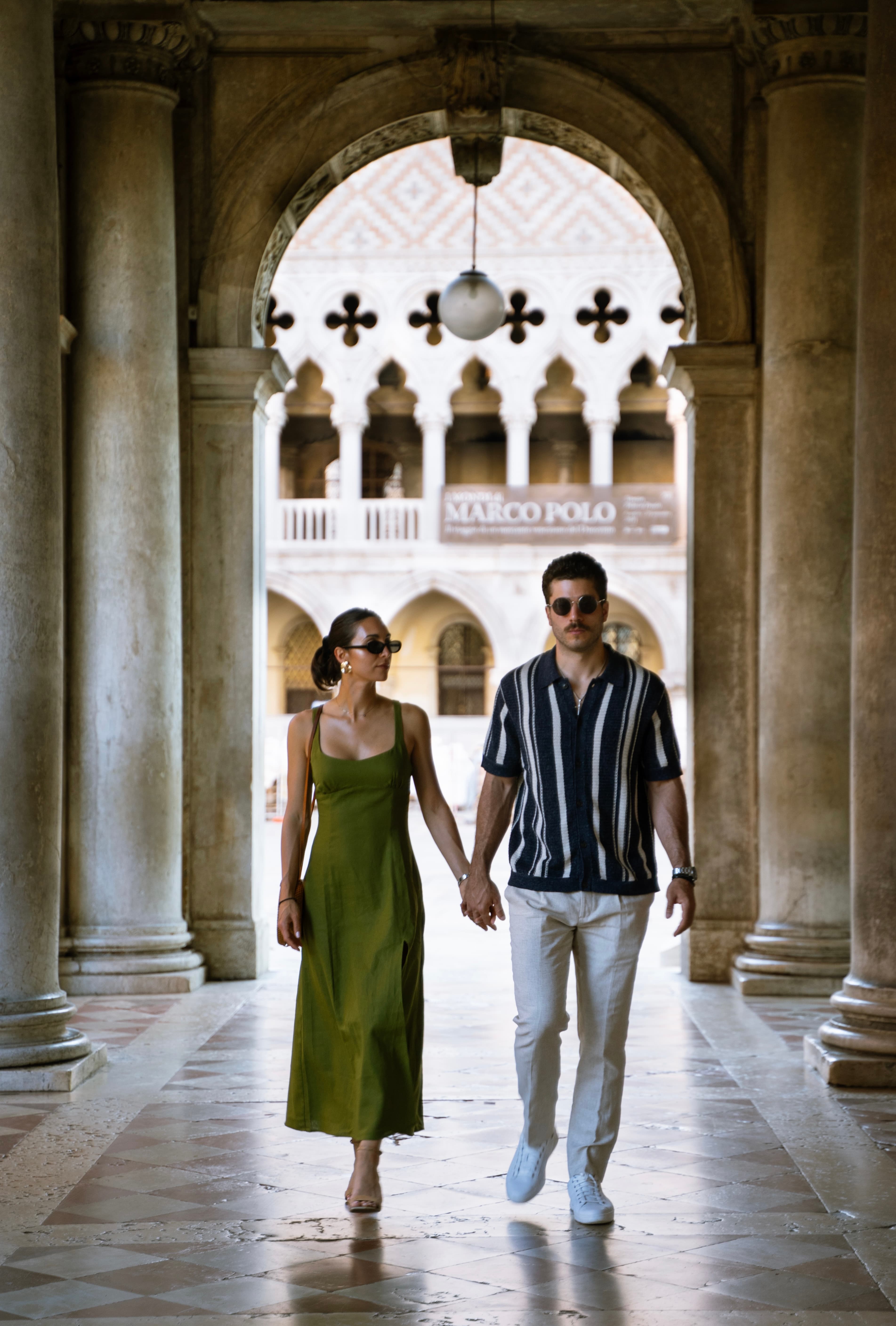 Advisor and partner walking hand in hand through a marble hall lined with columns