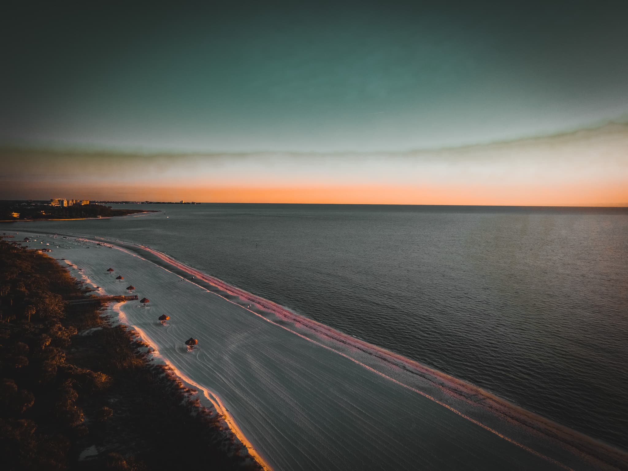 Aerial view of a wide empty beach and calm sea at sunset