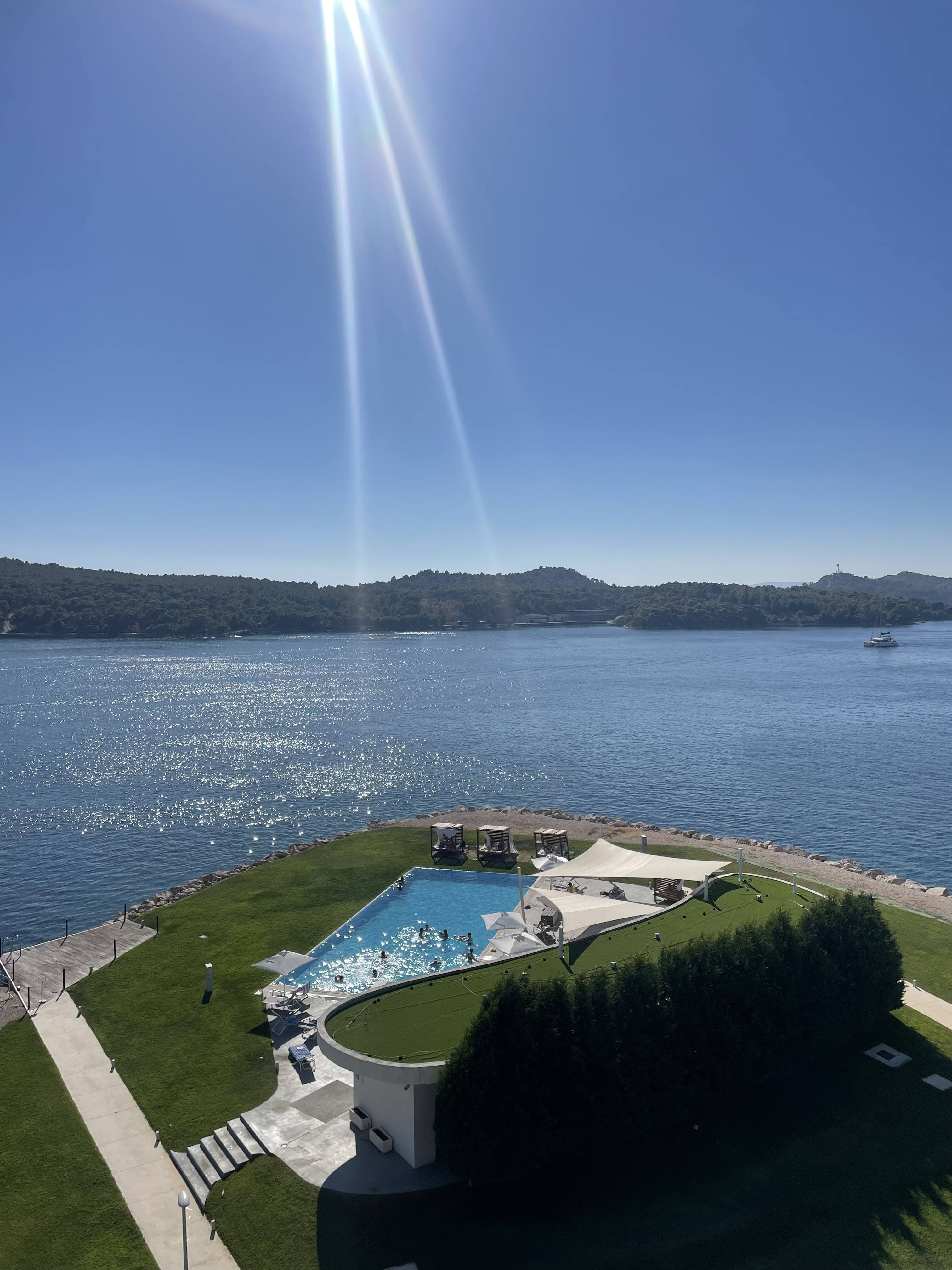 View of a hotel pool overlooking the sea on a sunny day