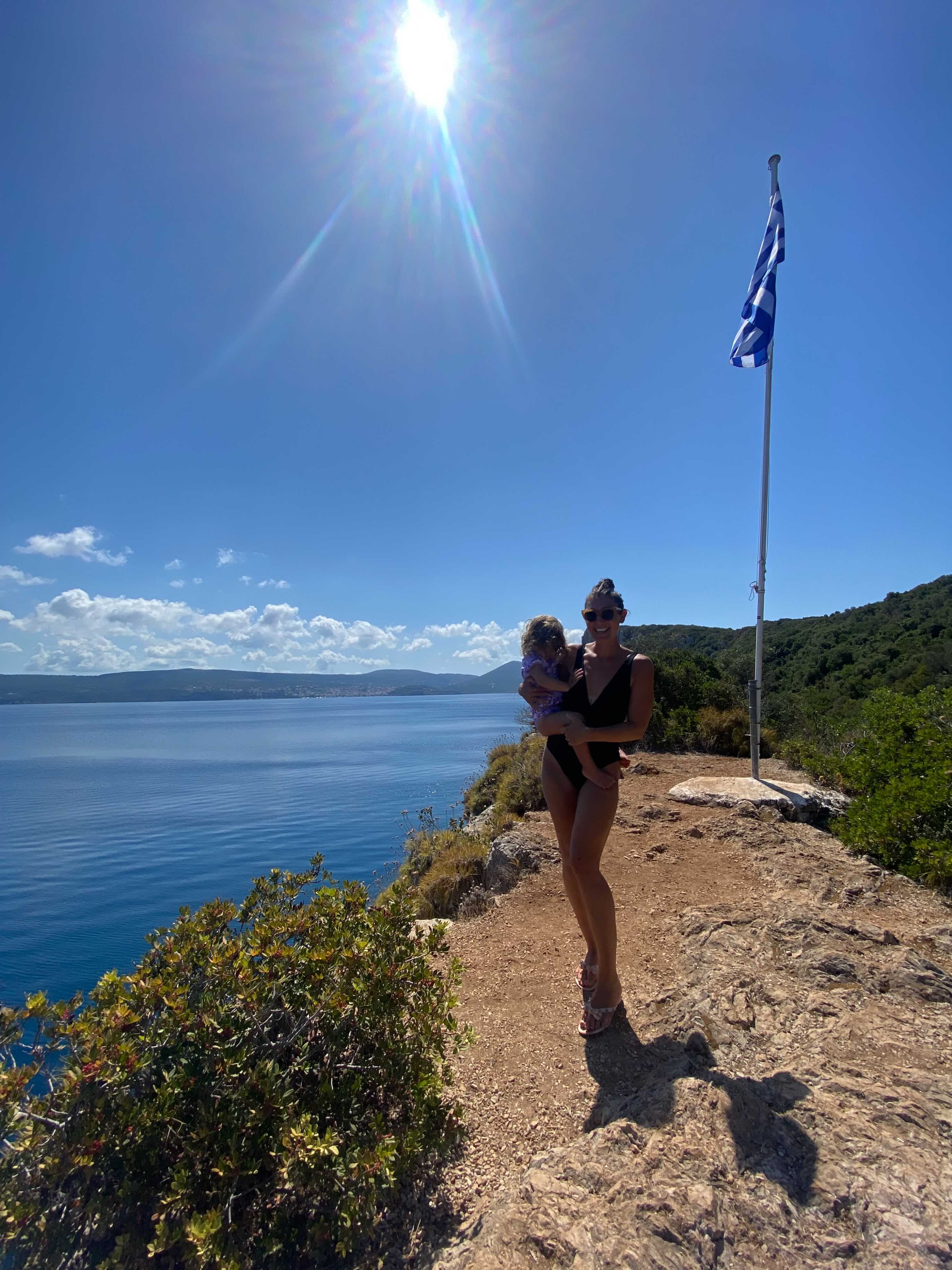 View of advisor holding a child on a hike along the coast under sunny skies
