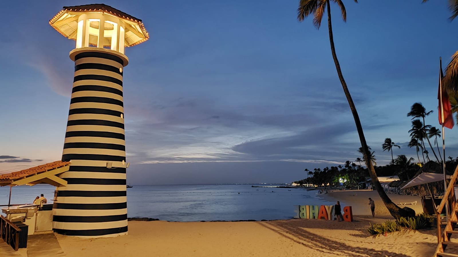 A lighthouse alongside a beach at night.