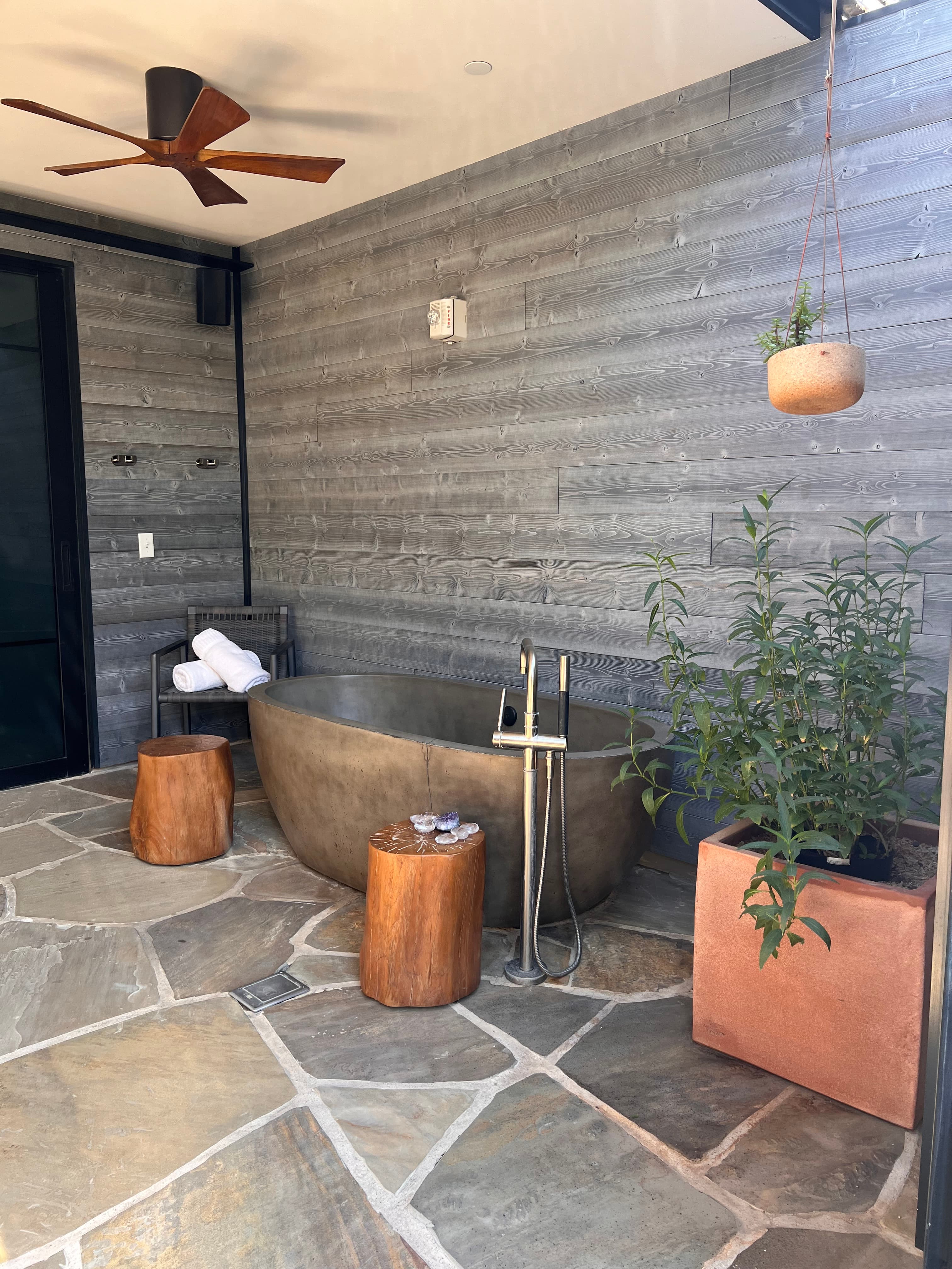 View of a modern outdoor bathtub against a grey wall