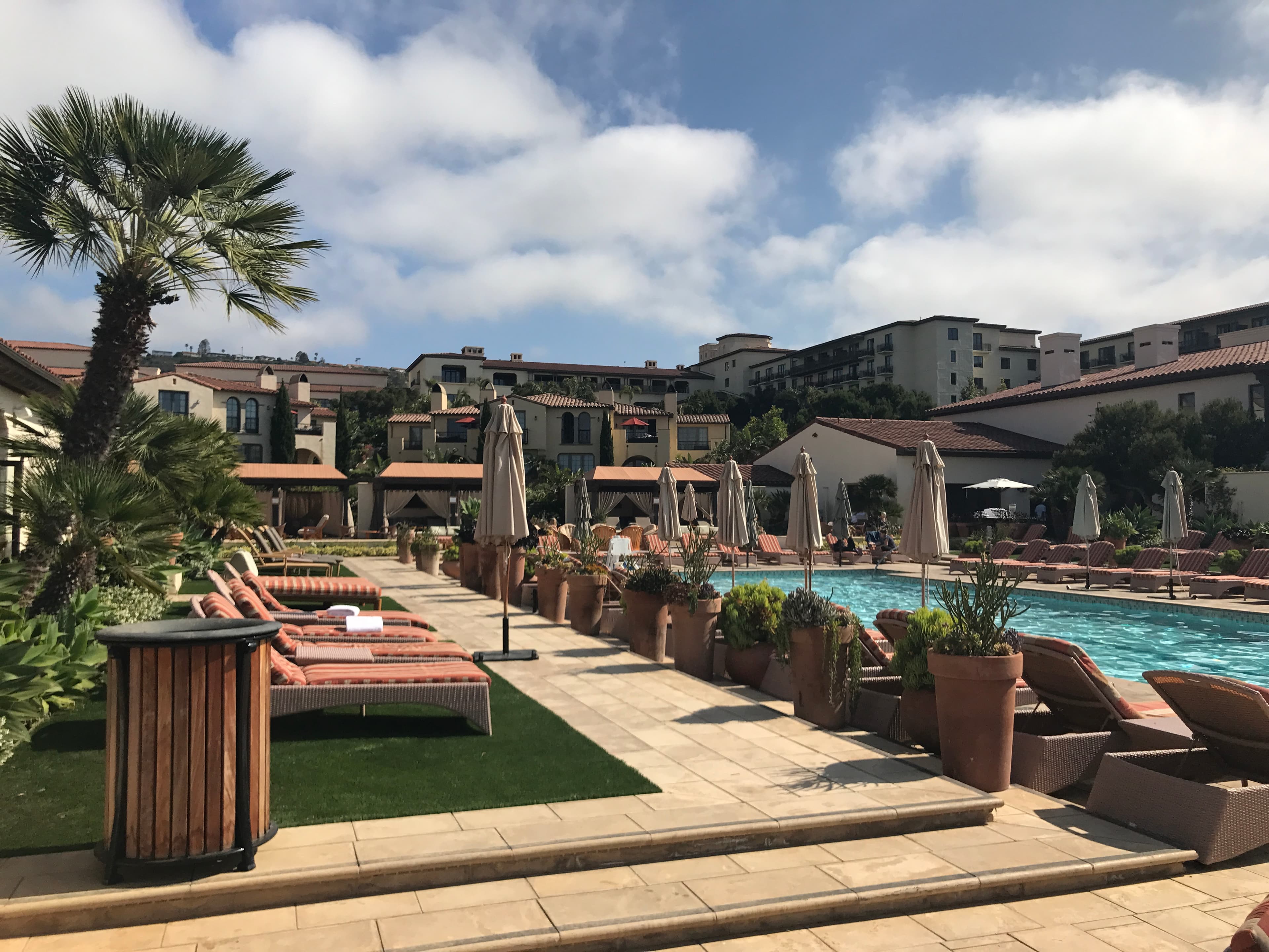 Empty resort pool lined with lounge chairs on a sunny day