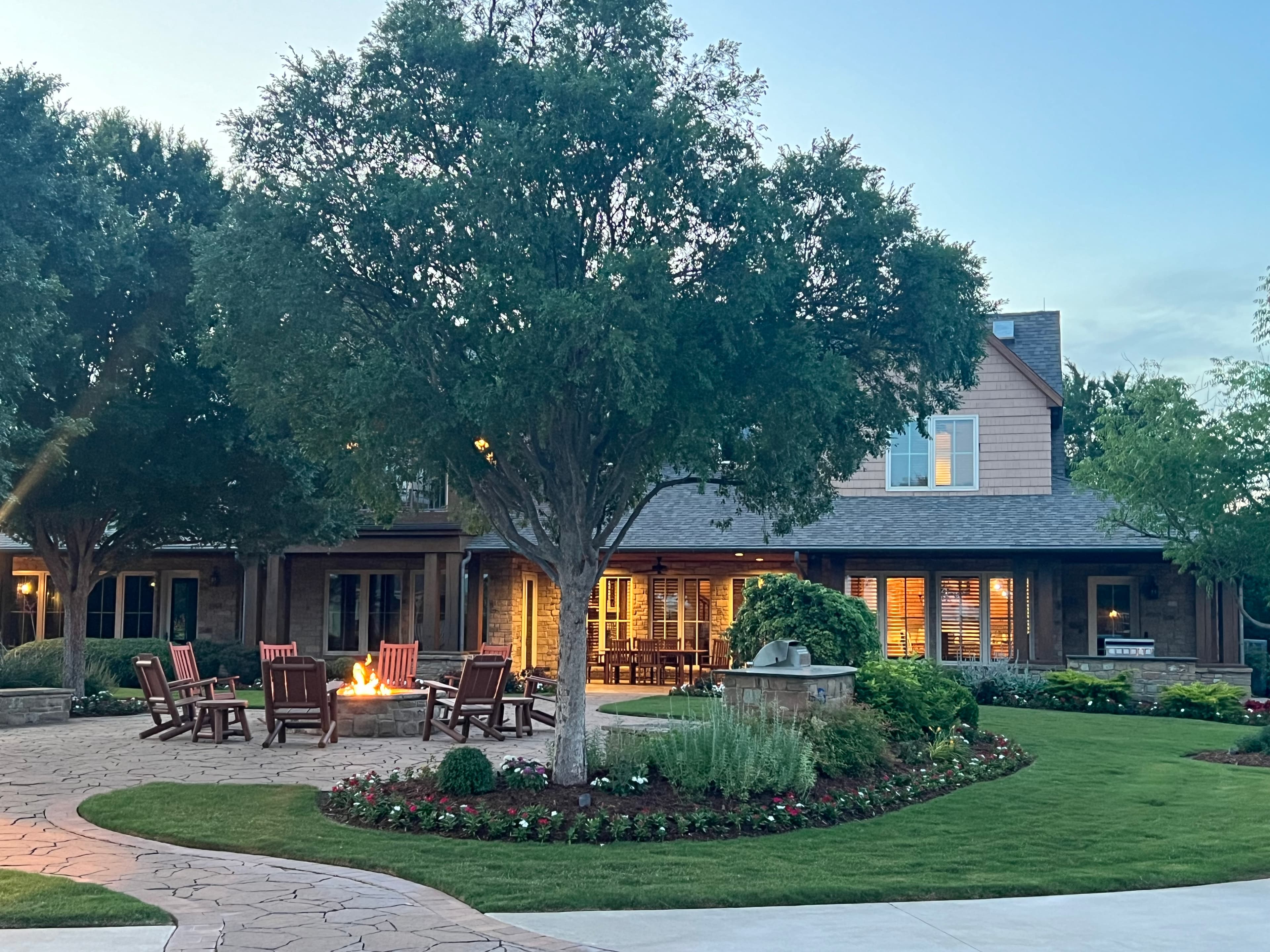 View of a beautiful house with a fire pit surrounded by Adirondack chairs 