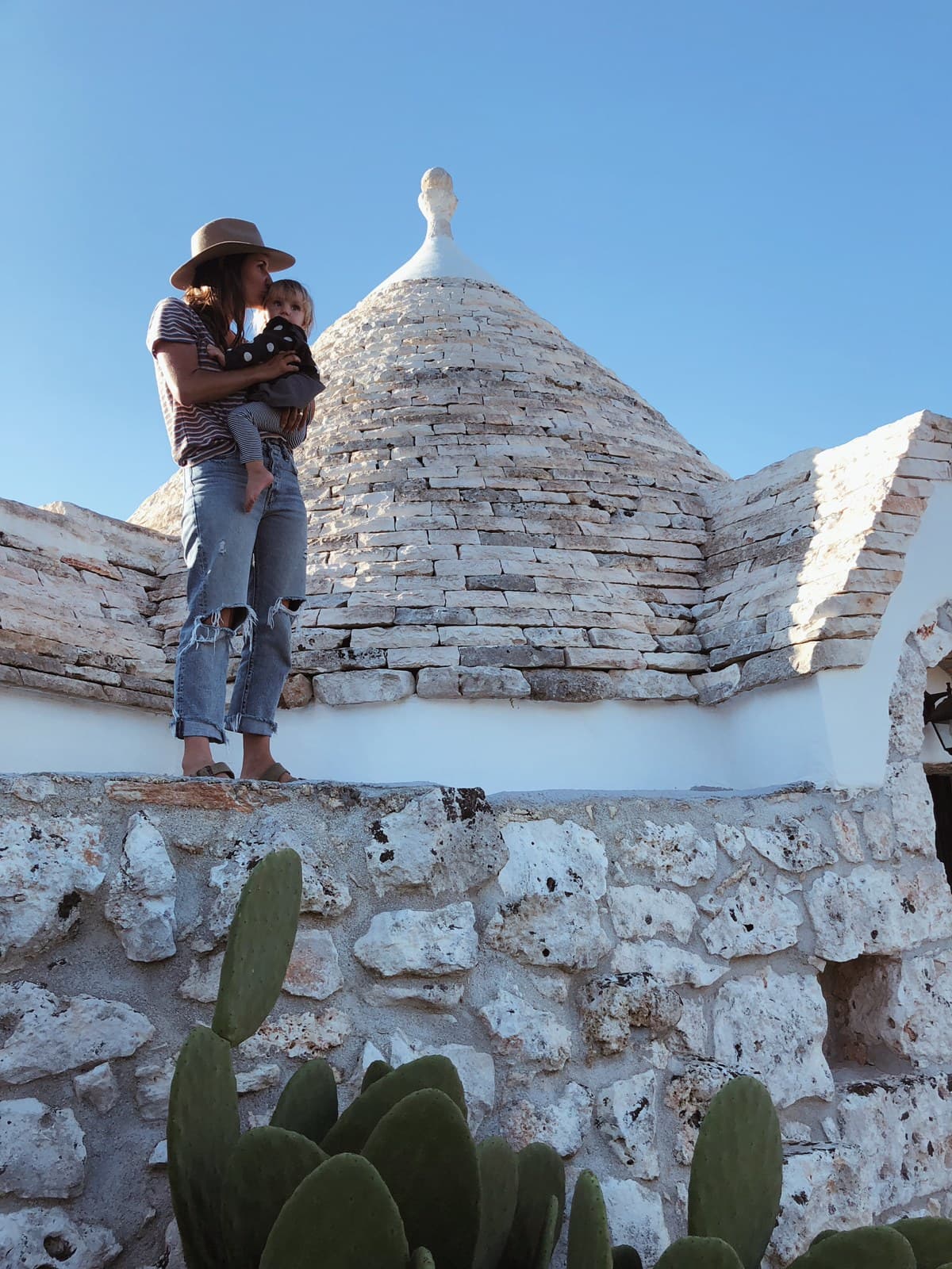 Advisor holding a toddler and standing on a stone wall.