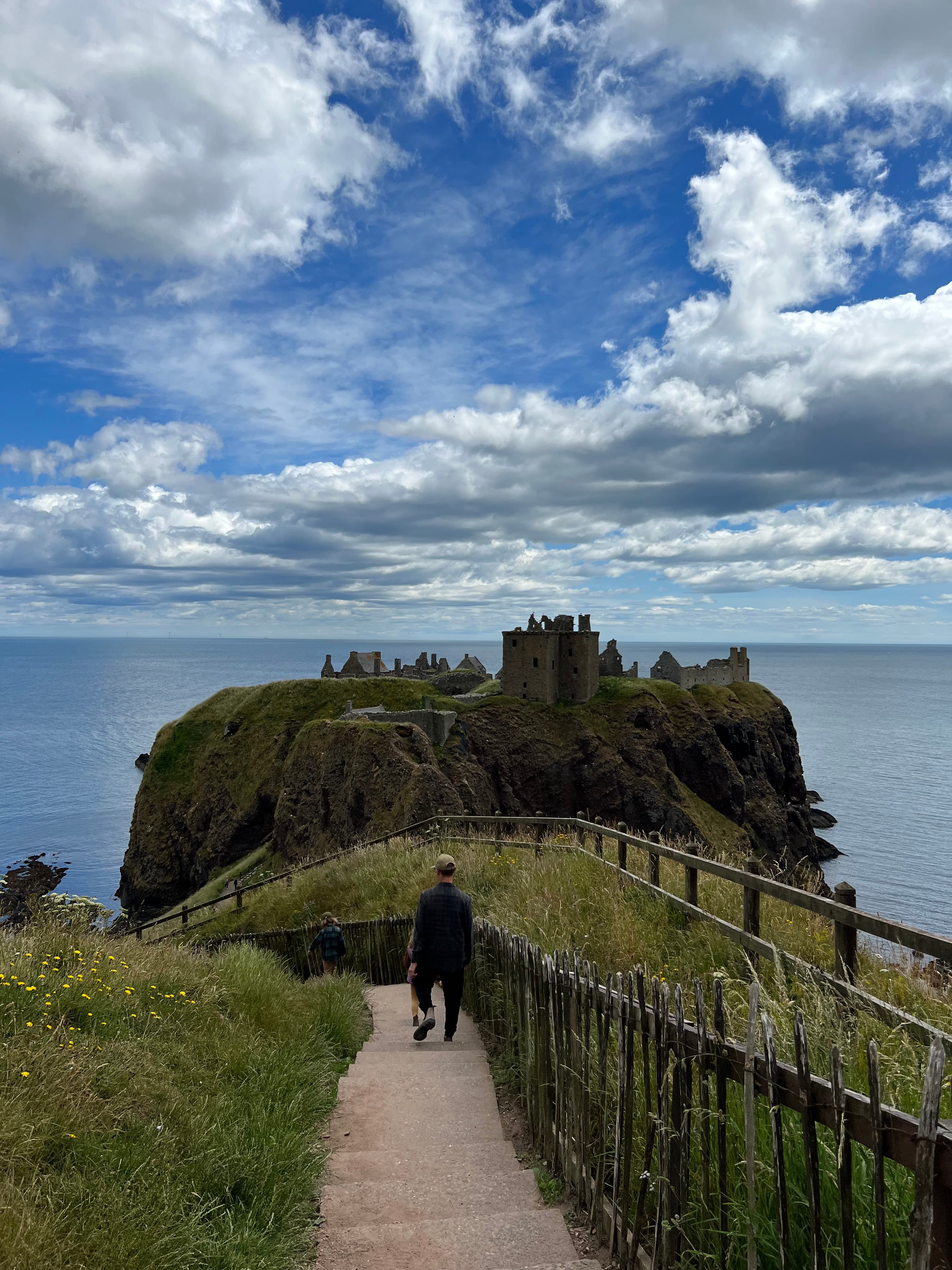 Advisor walking down stairs toward the coast with sea stacks in the background.