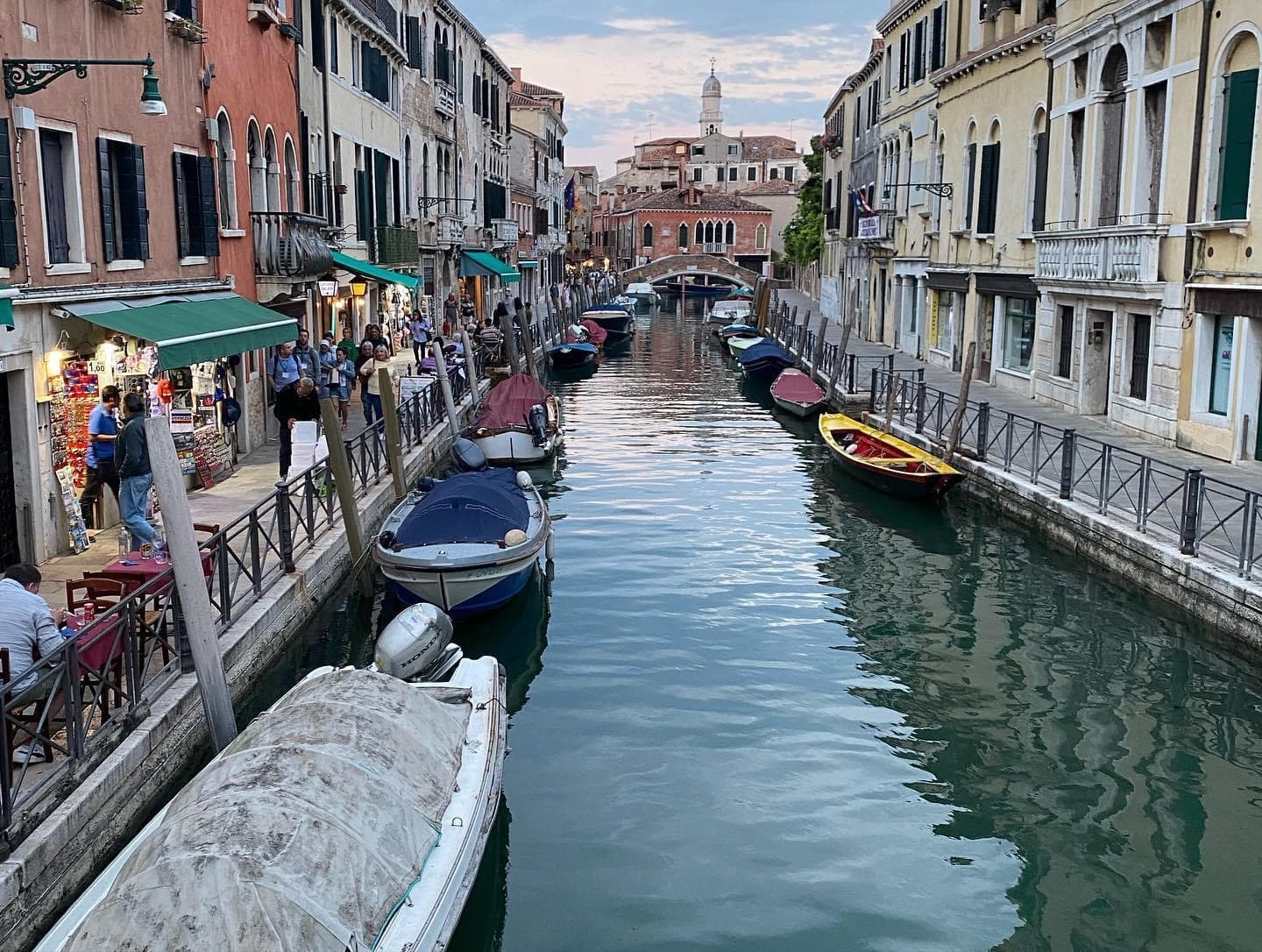 A canal running between city buildings with boats parked along it.